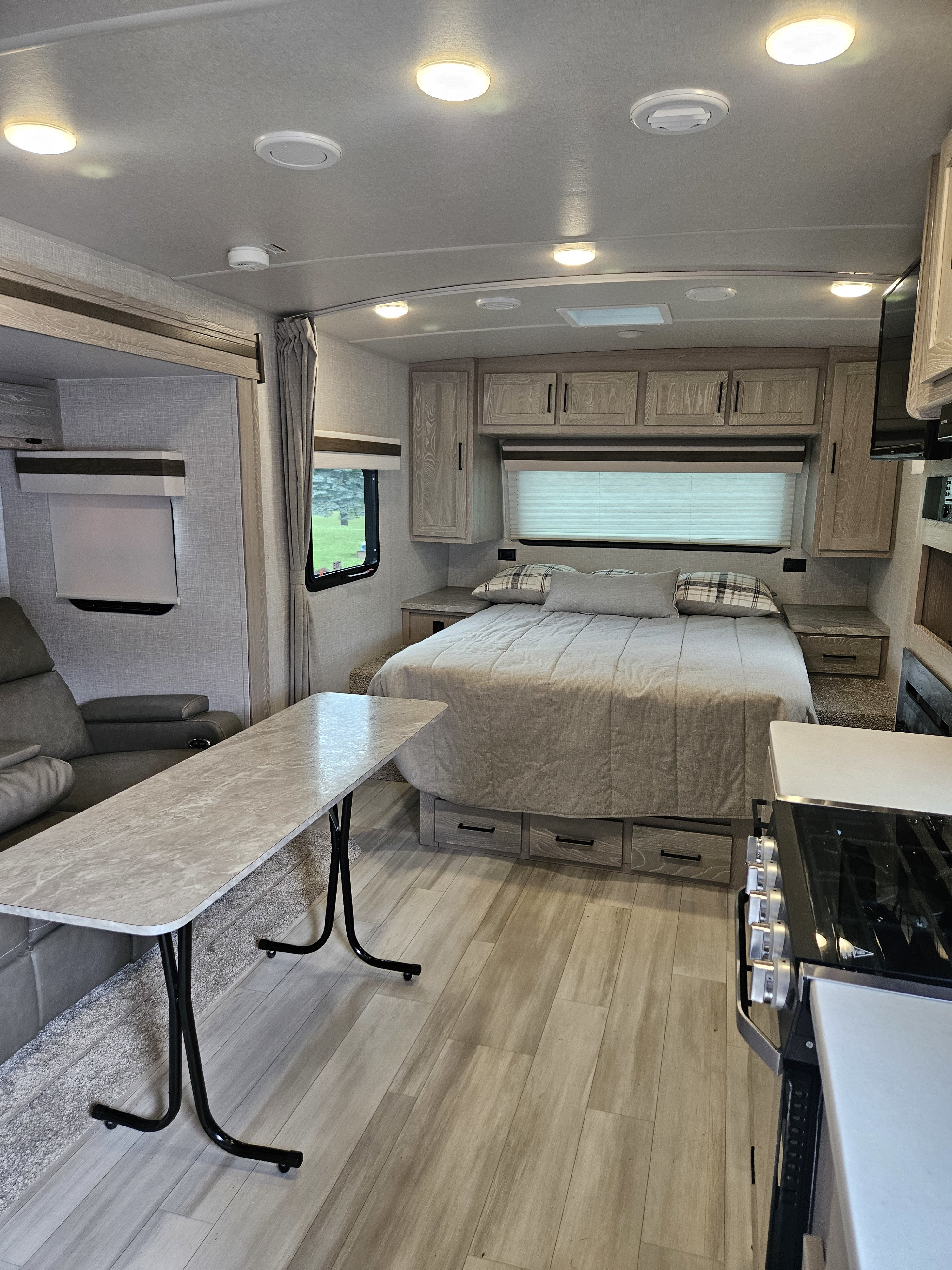 Explore this inviting RV rental interior: a comfy bedroom, spacious living area with table, and well-equipped kitchen.. Forest River Mini-Lite 2022