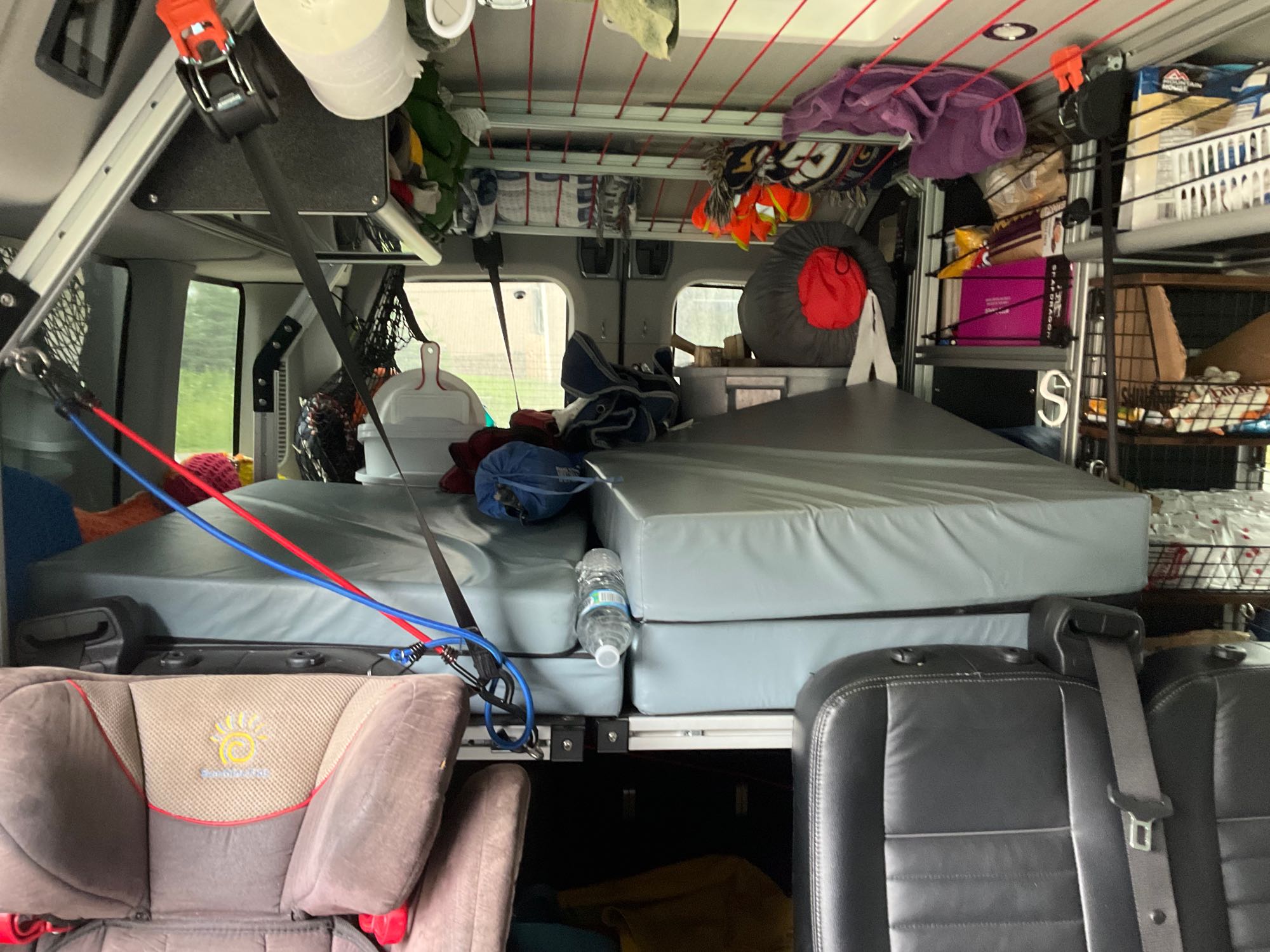 Custom RV rental interior featuring stacked beds, a child car seat, and ample overhead storage for travel gear.. Ford Transit Custom 2022