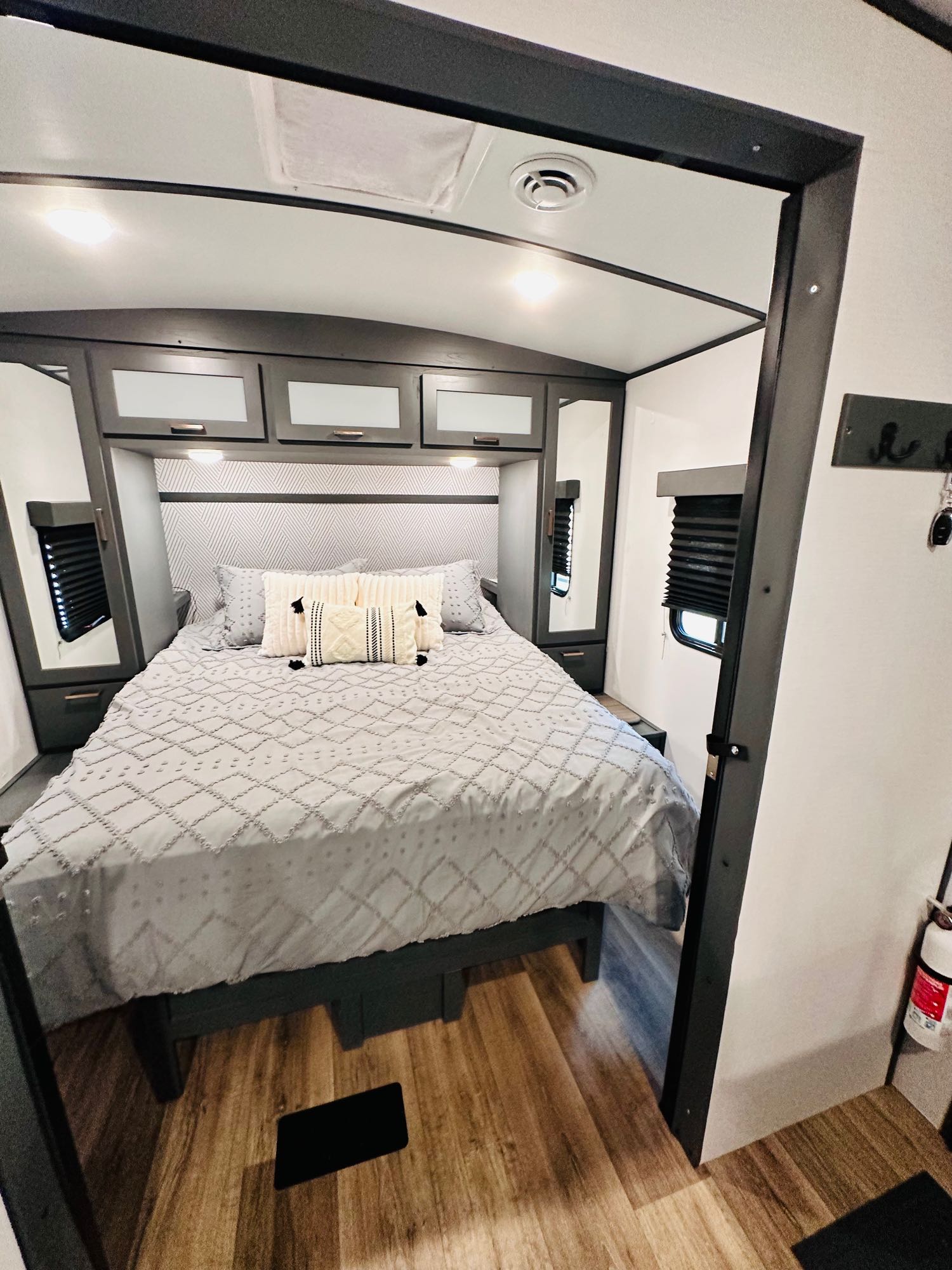 Relaxing RV rental bedroom with a comfy bed, overhead cabinets, and stylish gray & white decor.. Keystone RV Bullet Ultra Lite 2023