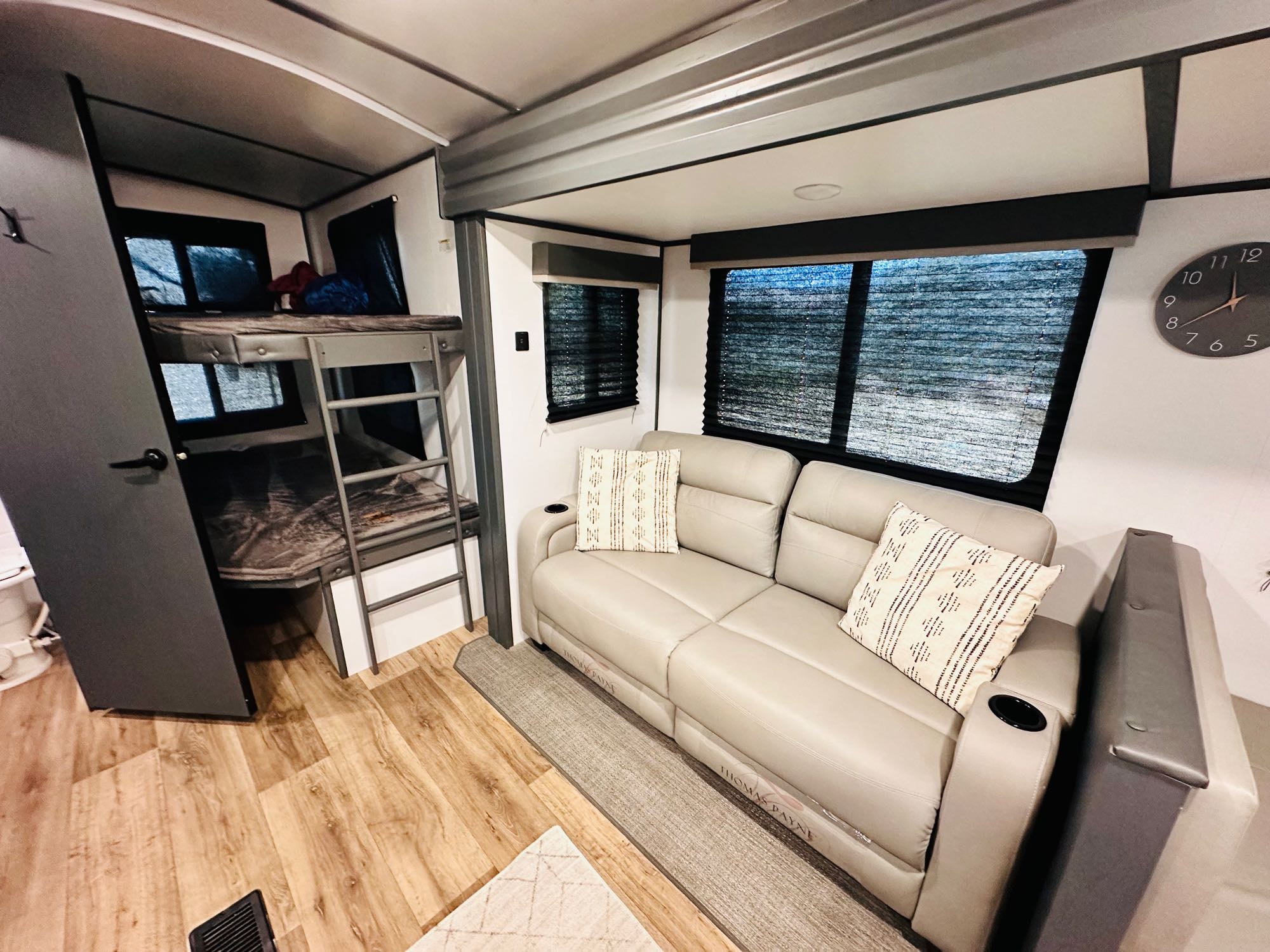 This RV rental offers a practical interior: light leather sofa, patterned pillows, bunk beds, and wood-look floor.. Keystone RV Bullet Ultra Lite 2023
