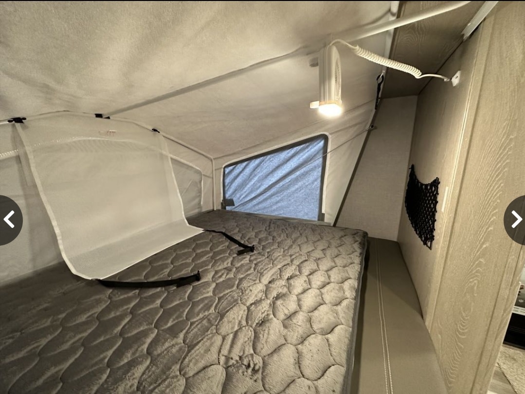 RV rental: View of a comfy sleeping area inside a pop-up camper, featuring a quilted mattress, overhead light, and storage.. Forest River Flagstaff Shamrock 2020