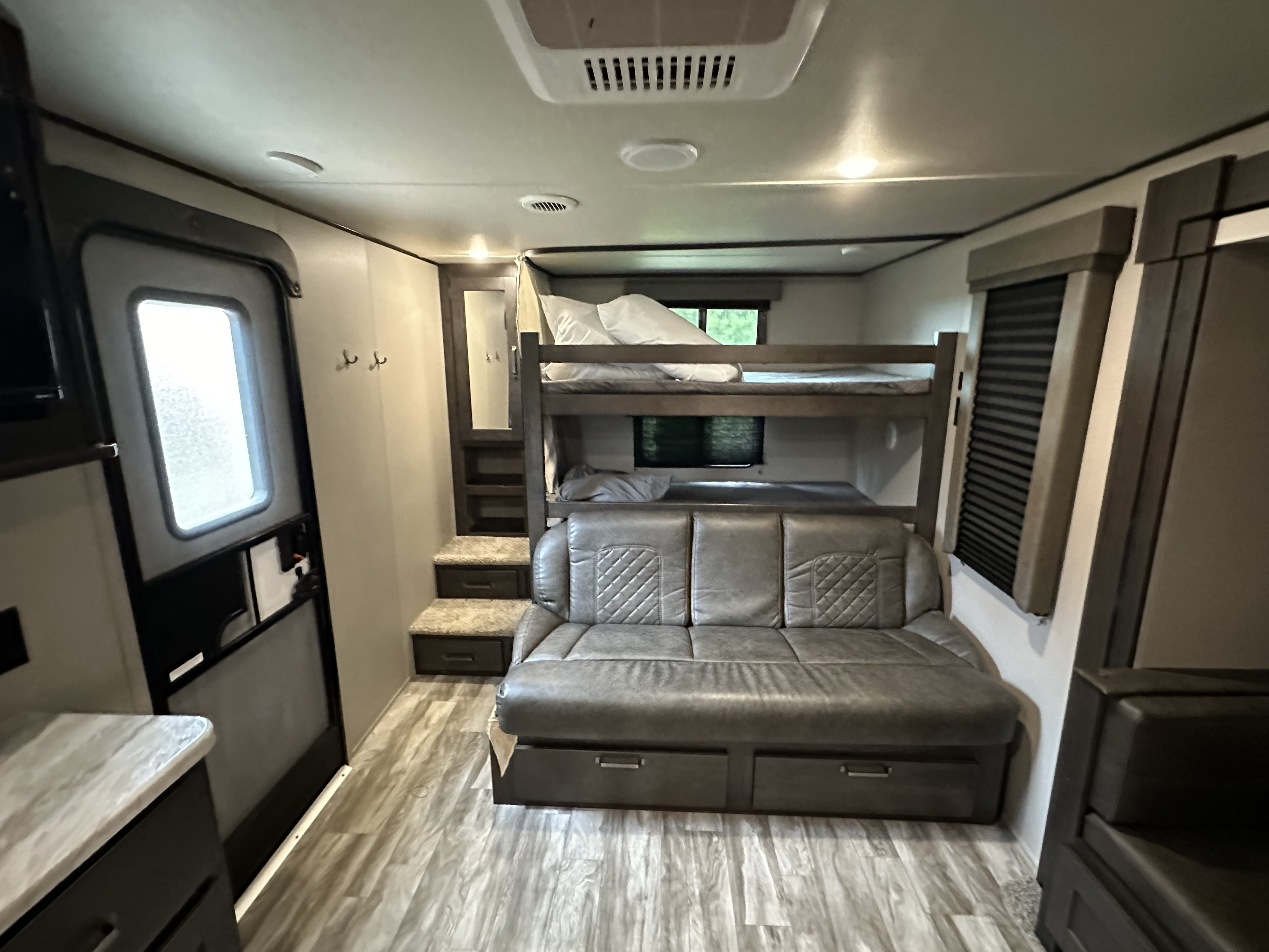 RV rental interior with modern bunk beds, a sofa bed with storage, and convenient entry door access.. Grand Design Transcend Xplor 2021