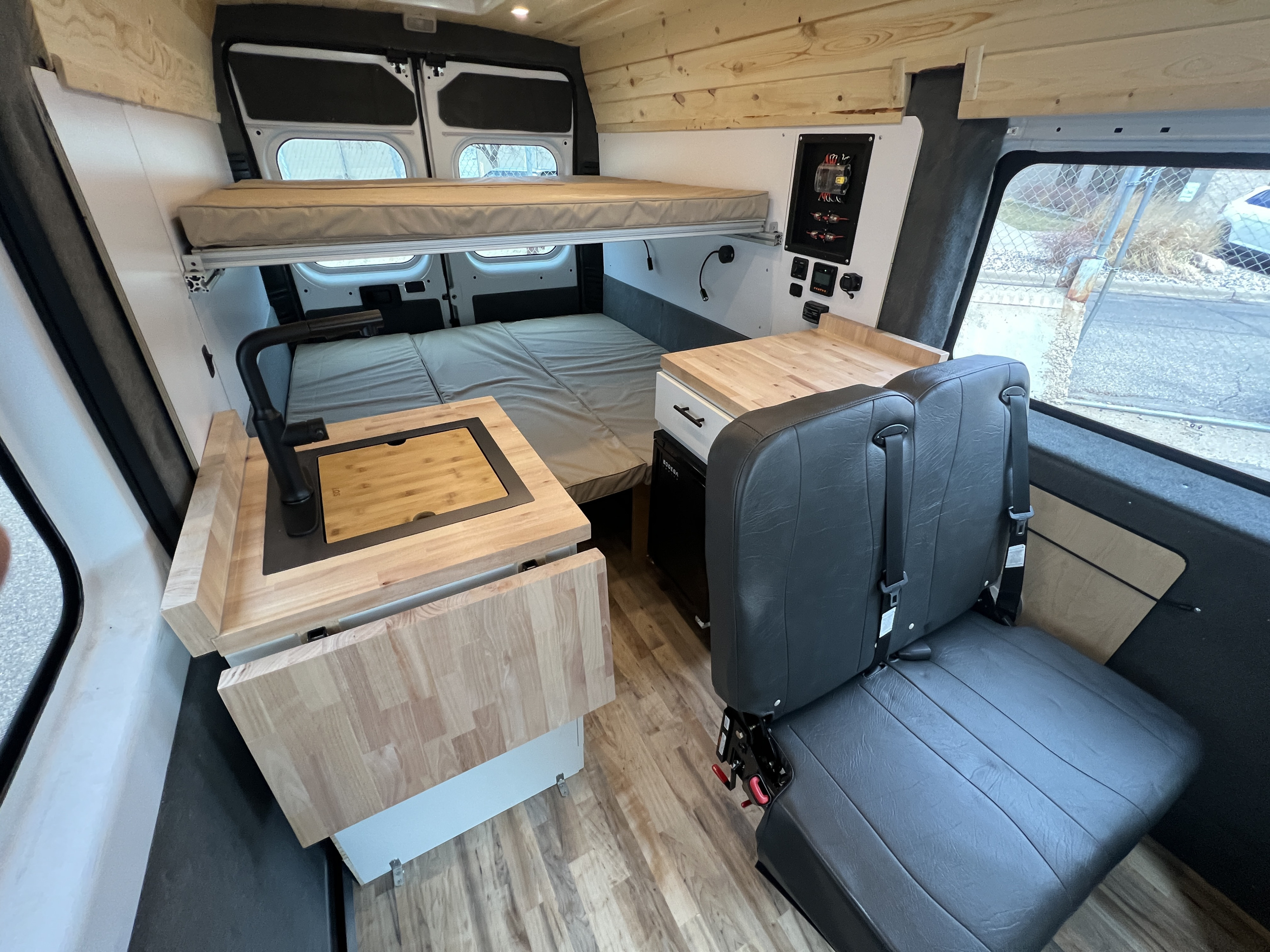 This RV rental features a full van interior with comfortable bunk beds, a compact kitchenette, and a control panel.. Ram Promaster 2500 2021