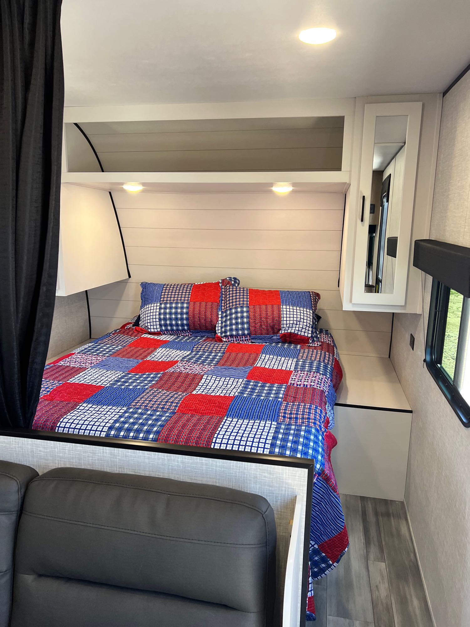 Cozy RV rental bedroom with a patriotic quilt, overhead storage, and a window view, offering comfortable mobile living.. Jayco Jay Flight SLX 2024