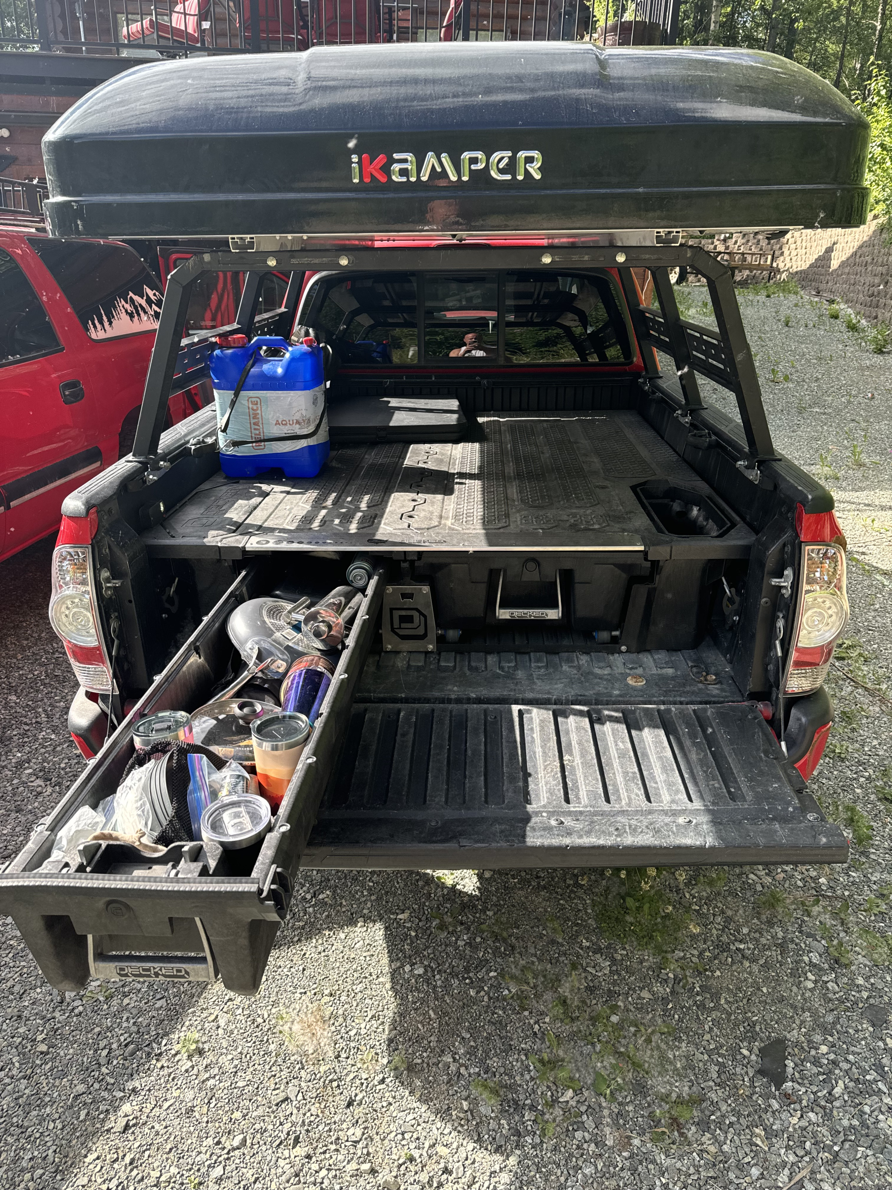 Ready for adventure! A truck bed with Decked storage, iKamper roof tent, and water jug for an overlanding RV rental setup.. toyota Tacoma 2006