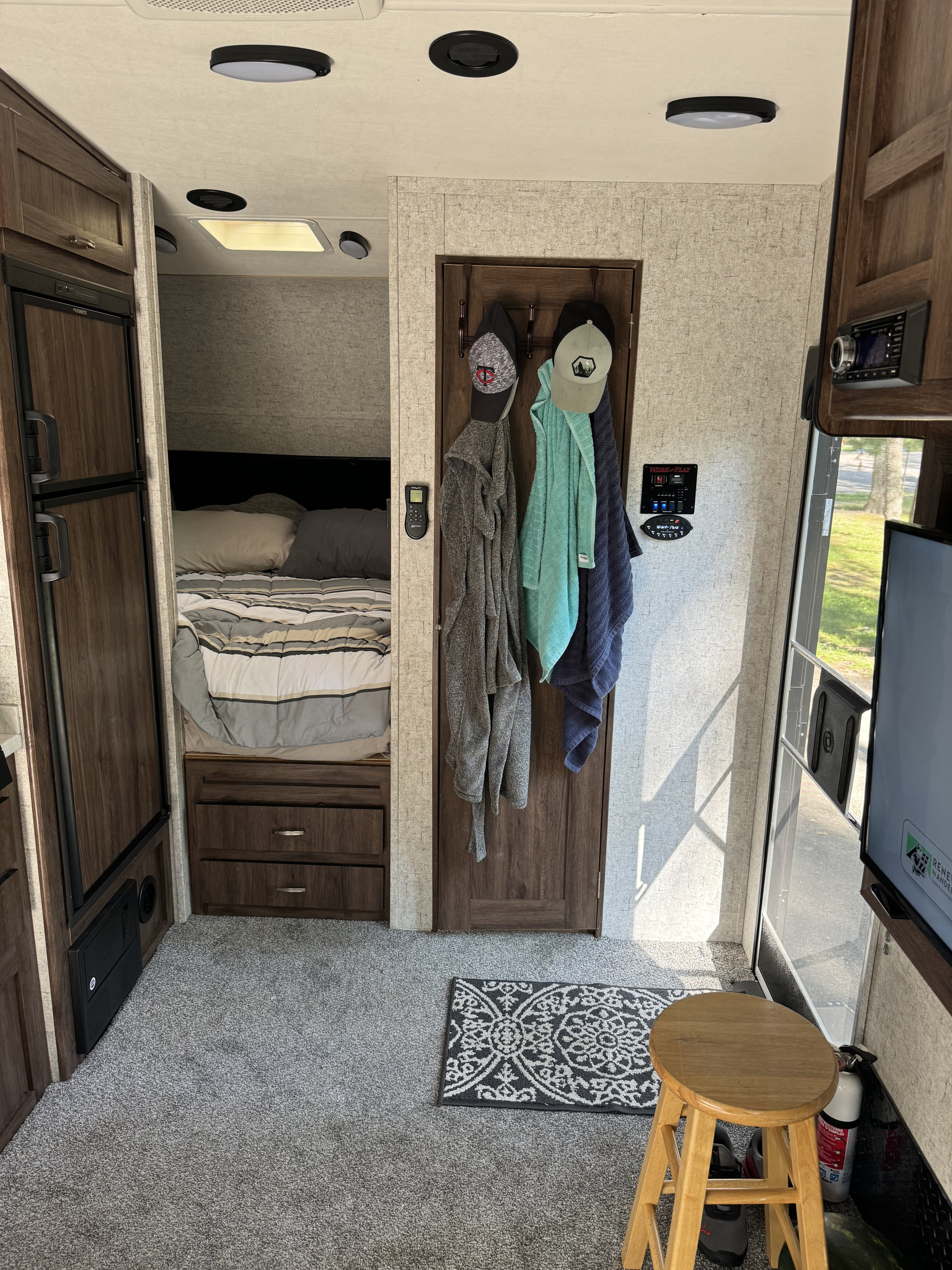 A clear view inside an RV rental, showcasing the bedroom, Dometic fridge, control panel, and inviting carpeted floor.. Forest River Work And Play 2019
