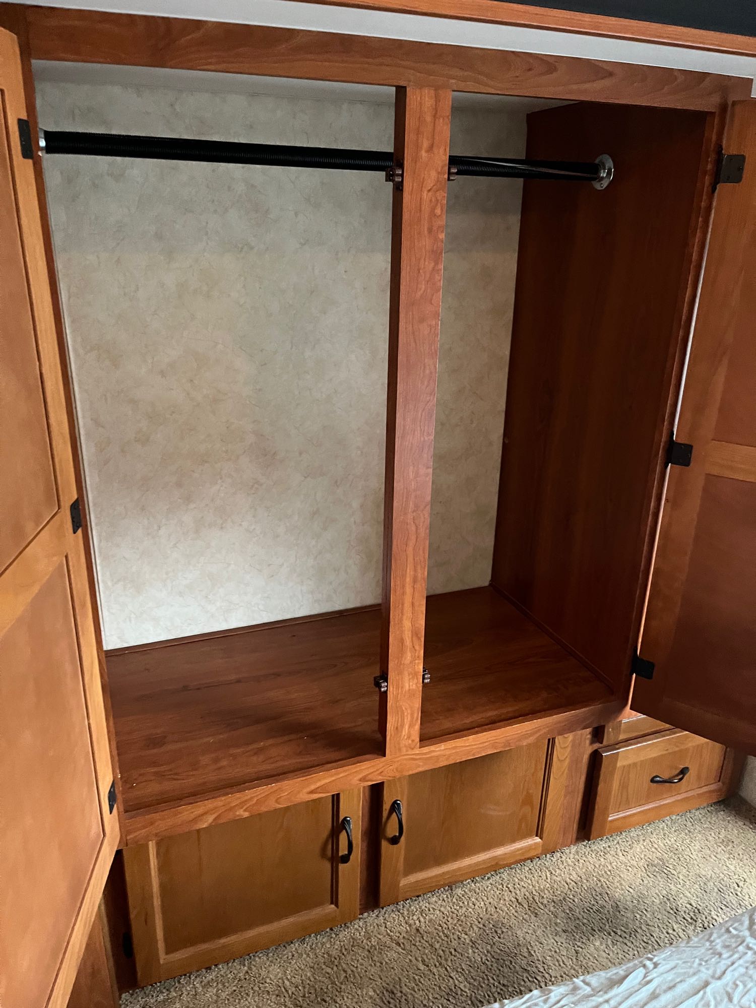 Inside an RV rental: a practical wooden wardrobe featuring hanging rods, lower cabinets, and drawers for efficient storage.. Coachmen Freelander 2011