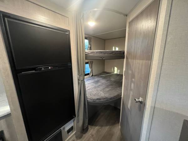 RV rental: Compact fridge on left. A curtained doorway on the right leads to a bunk bed area with two beds.. Coachmen Catalina 2022