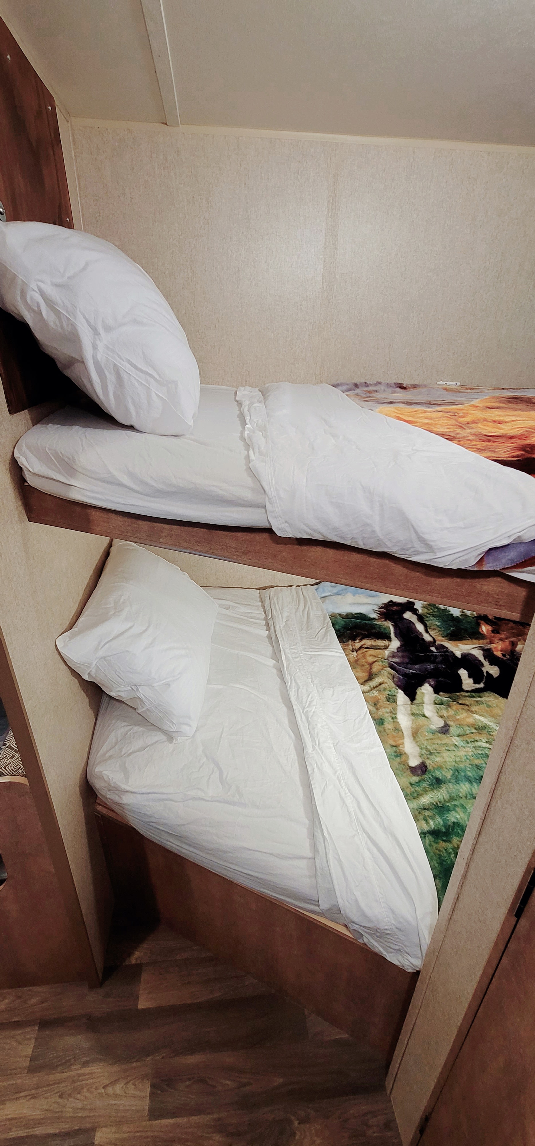Cozy RV rental bunk beds, fully made with white linens. Lower bunk reveals a horse-themed blanket. Ideal for family travel.. Starcraft AR-One Maxx 2017