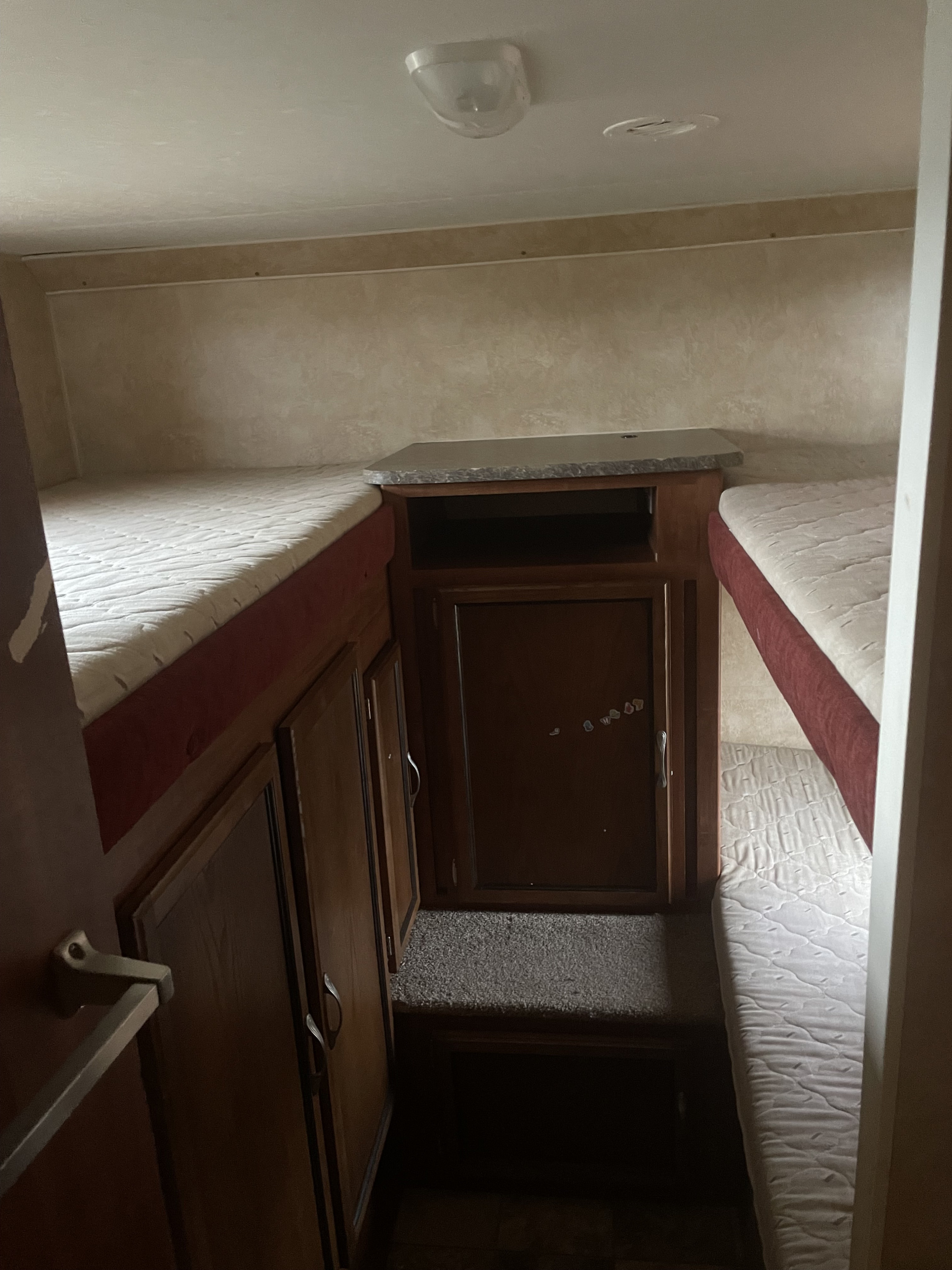 Inside this RV rental, a practical bunkhouse features two beds, central counter with storage, and carpeted floor space.. Jayco Jay Feather 2011