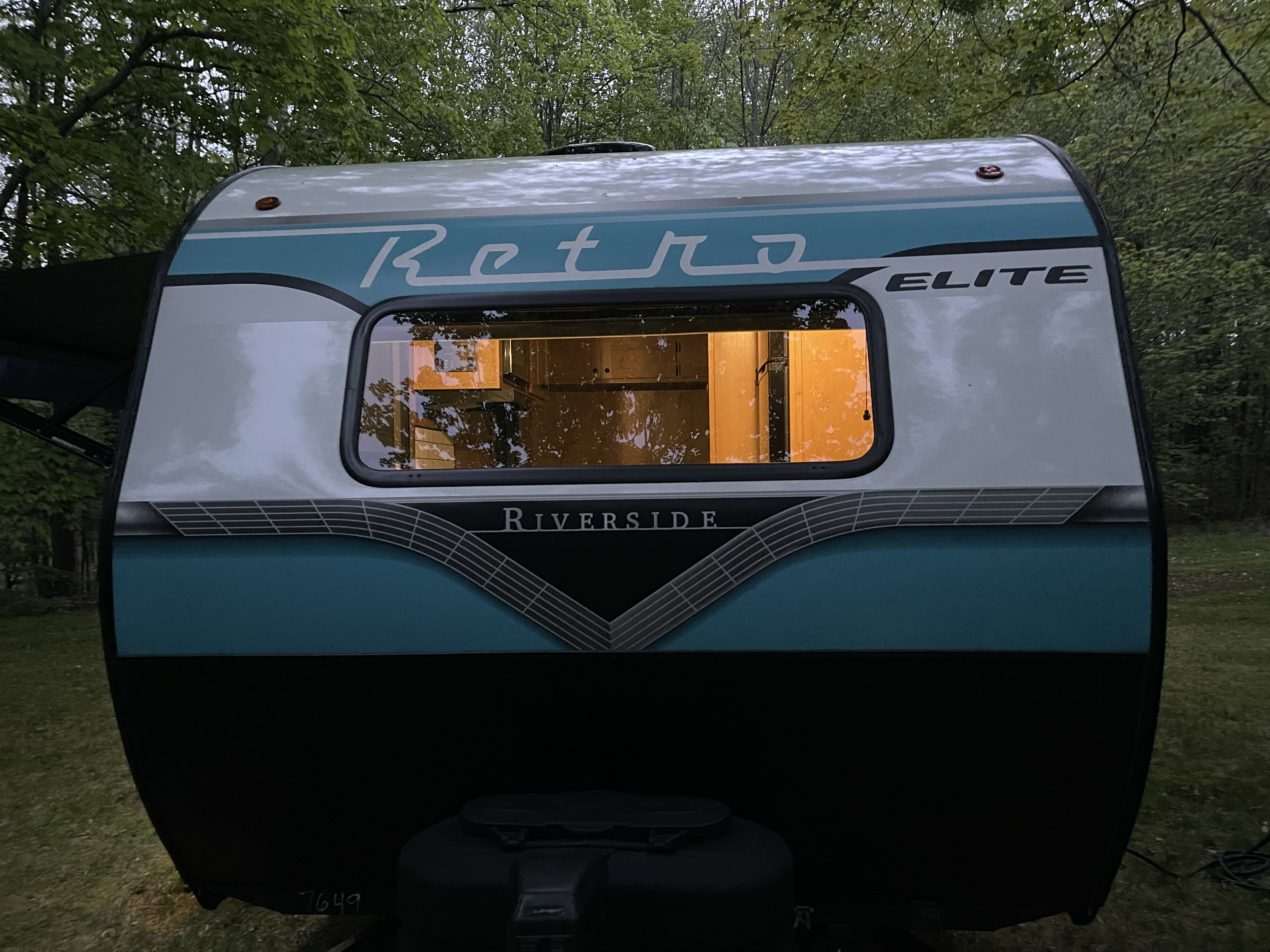Cozy retro RV rental (Riverside Elite travel trailer) glowing at dusk, perfect for a camping adventure.. Riverside Retro Elite 2024