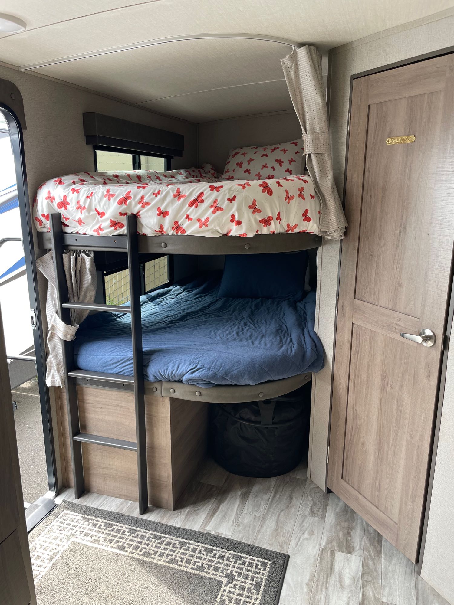 Cozy RV rental interior with bunk beds: top bed has fun butterfly bedding, bottom bed features blue. Ideal for family adventures.. Grand Design Imagine 2022