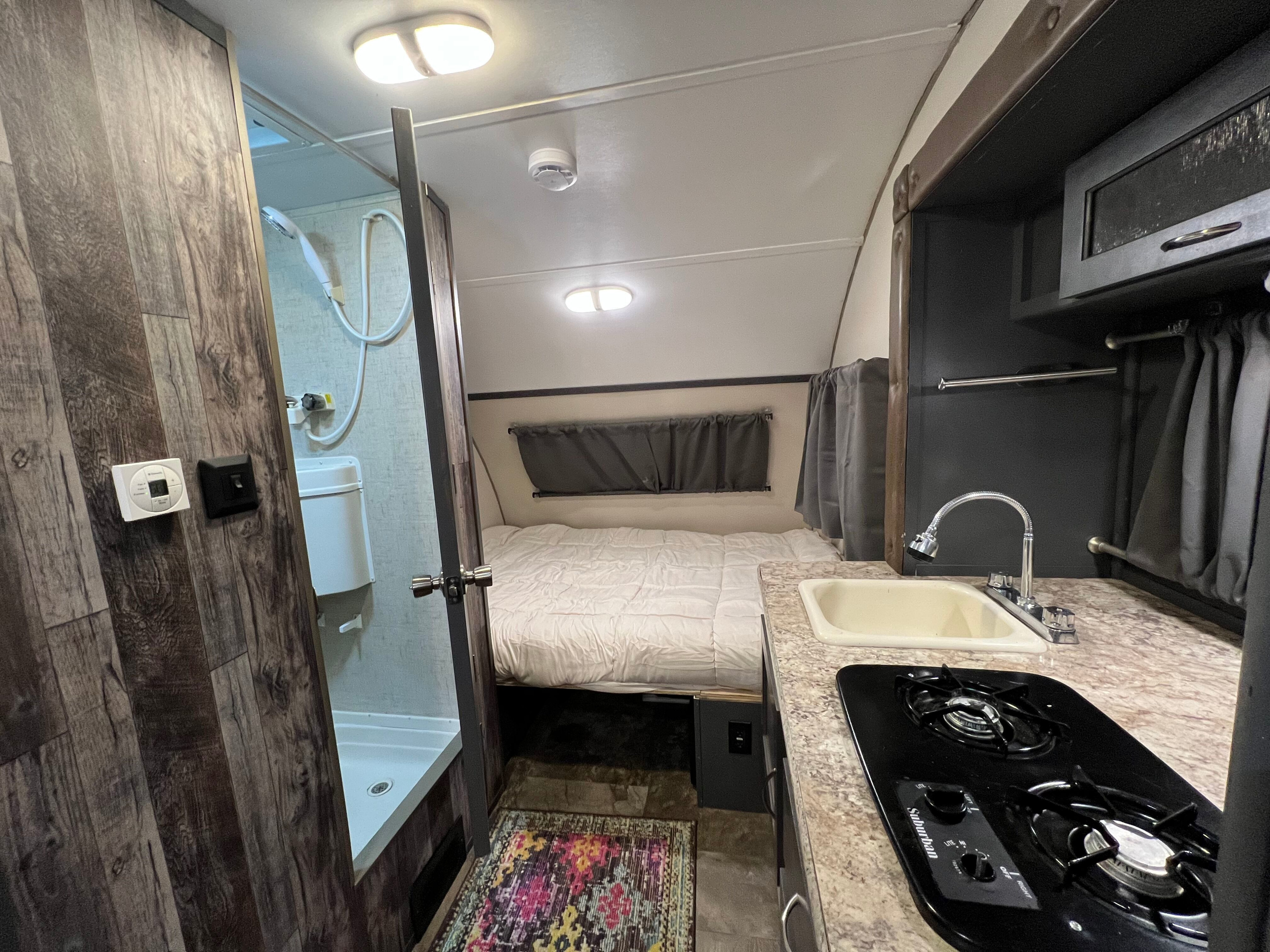 This clean rv rental interior shows a bed, kitchen with sink/stove, and a compact shower/toilet area.. R-Pod Hood River Edition 2017