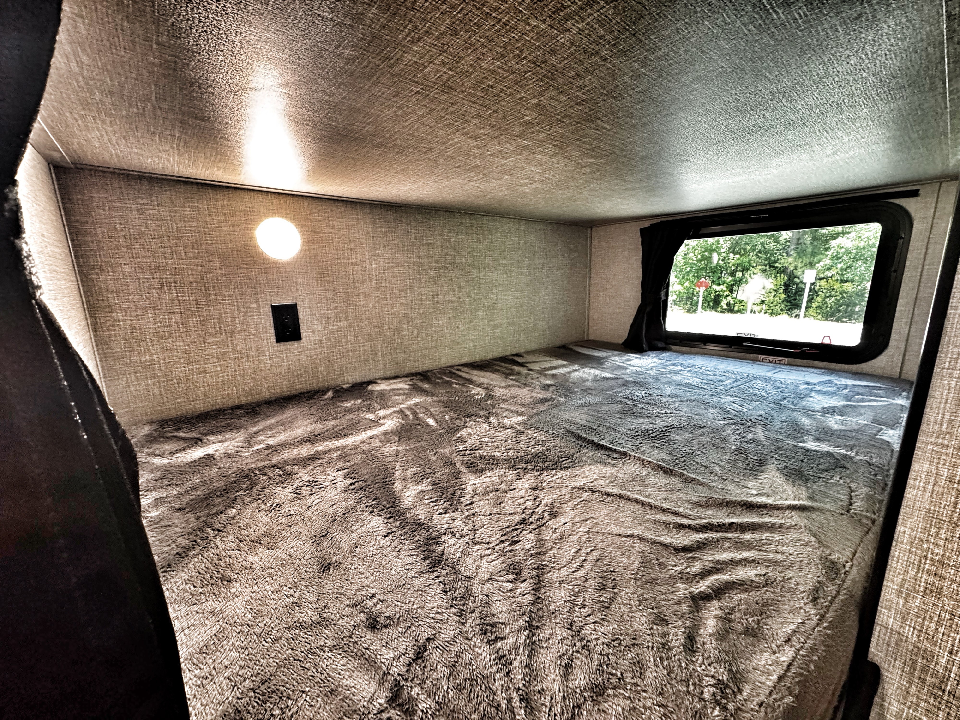 RV rental: A cozy, compact bunk bed space with a soft blanket, wall light, and window view.. Jayco Jay Flight SLX 2022