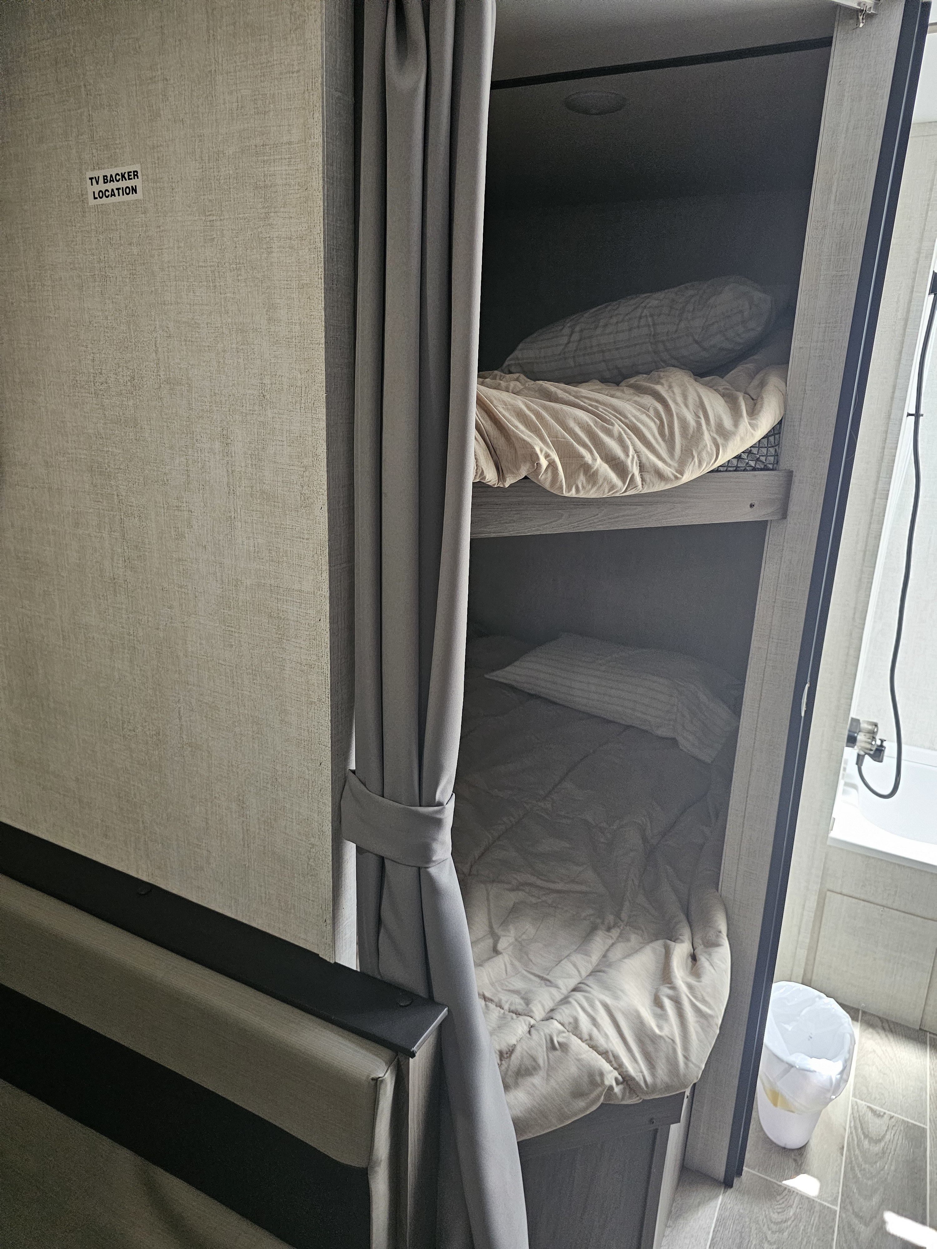 RV rental bunk beds, complete with a privacy curtain & TV backer location. A peek into the compact bathroom is on the right.. Gulf Stream Ameri-Lite 2022