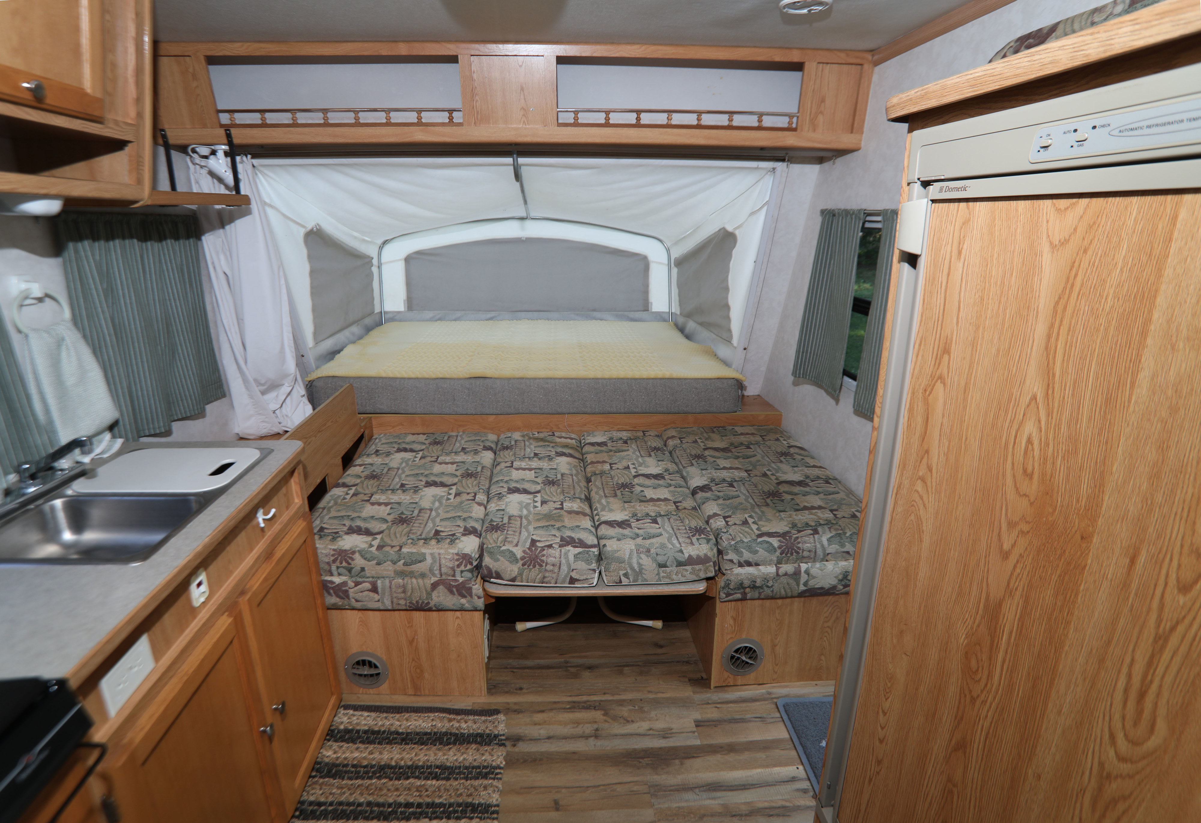 This RV rental's pop-up camper interior features a cozy bed, dinette, compact kitchenette, and refrigerator.. R-Vision Trail-Lite Trail-Cruiser 2003