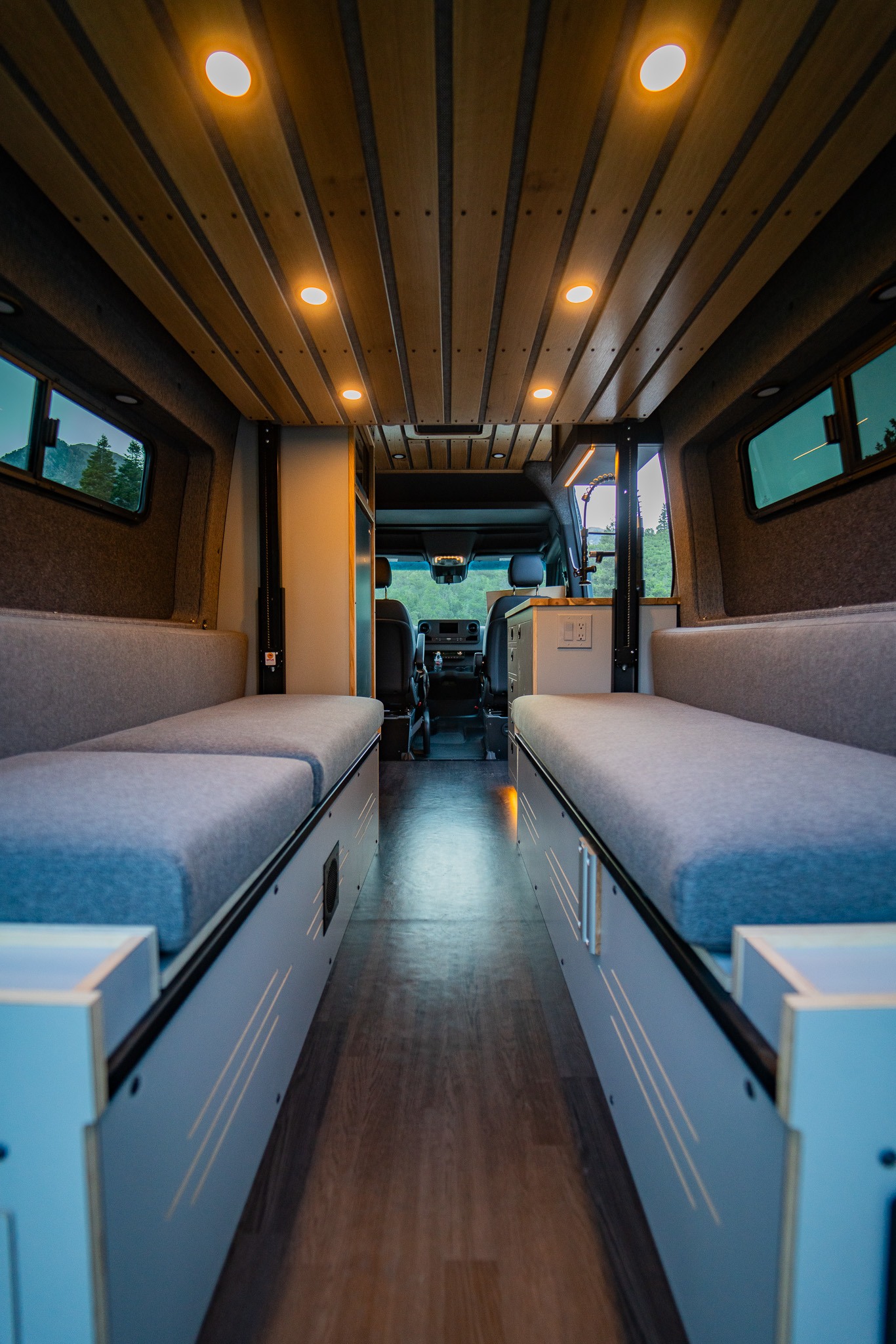 Cozy RV rental interior with comfy benches, wood ceiling, & warm lights. Perfect camper van for adventure!. Mercedes-Benz Sprinter 2022