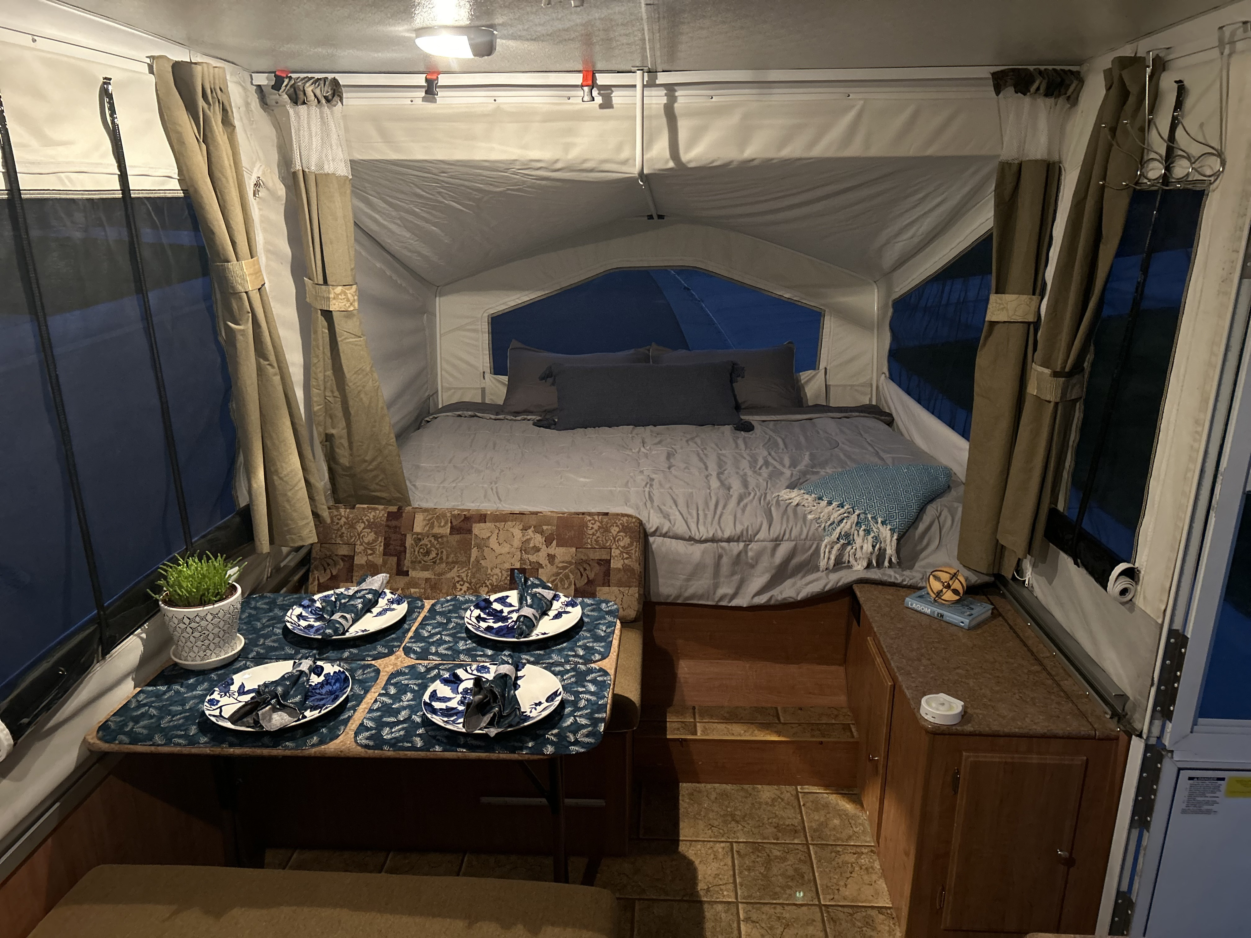 Explore this RV rental's cozy pop-up camper interior with a bed and dining area, ideal for glamping trips.. Forest River Rockwood Freedom 2012