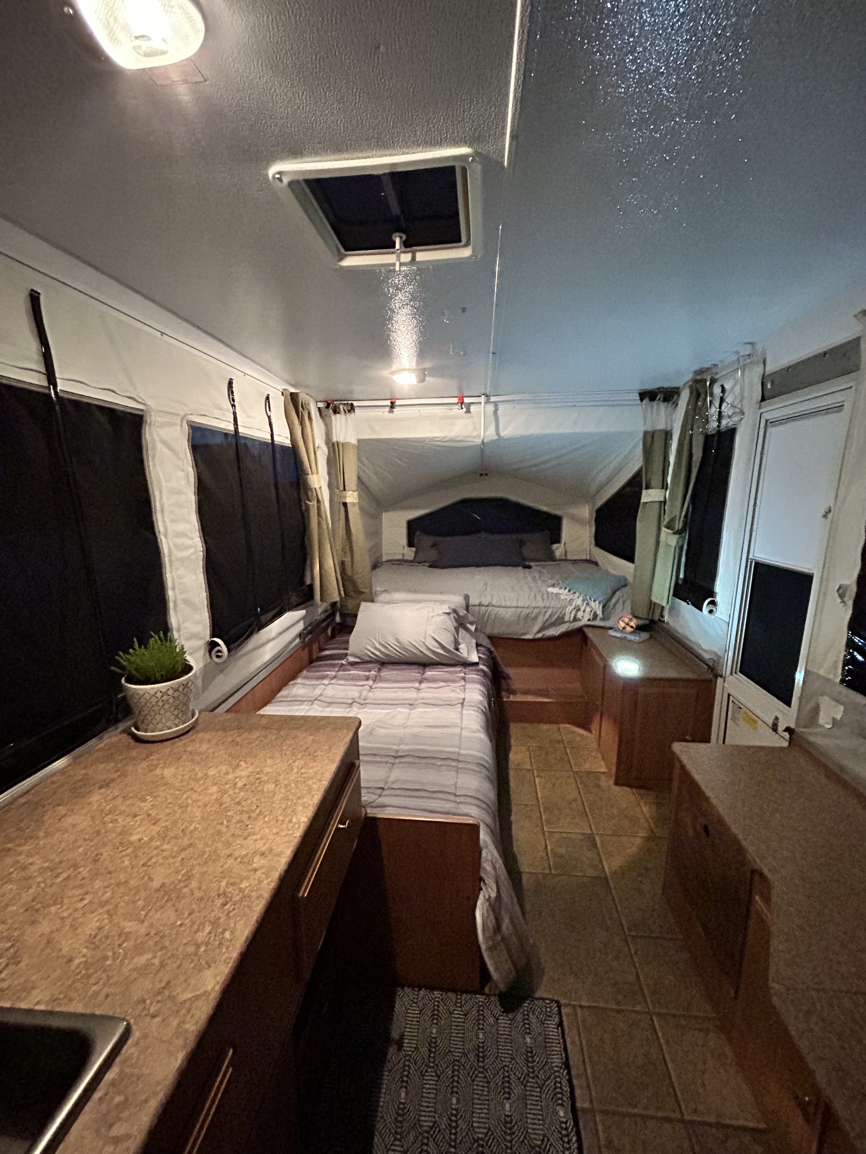 Inside a comfortable RV rental: two beds, tiled floor, and a compact kitchen counter. Ready for adventure!. Forest River Rockwood Freedom 2012