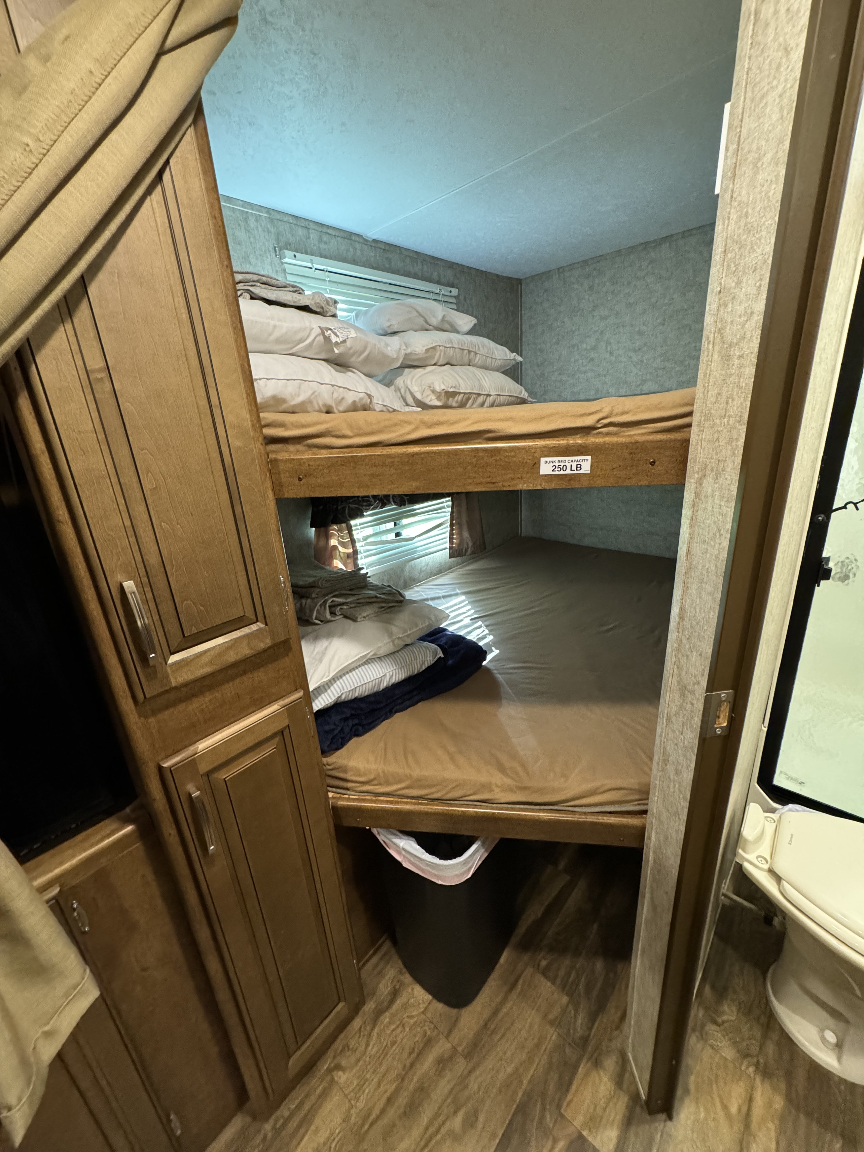 This RV rental features stacked bunk beds with pillows, bedding, a side cabinet, and a window. Bunk capacity: 250 LB.. Forest River Wildcat 2017