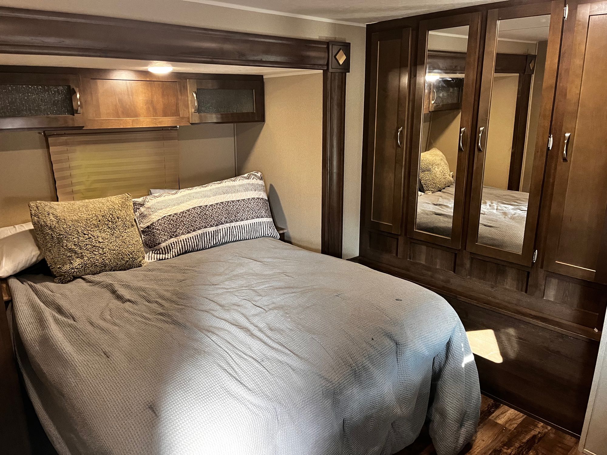 Cozy RV rental bedroom with a comfortable bed, overhead storage cabinets, and mirrored wardrobe for your travels.. Forest River Palomino Puma XLE 2017