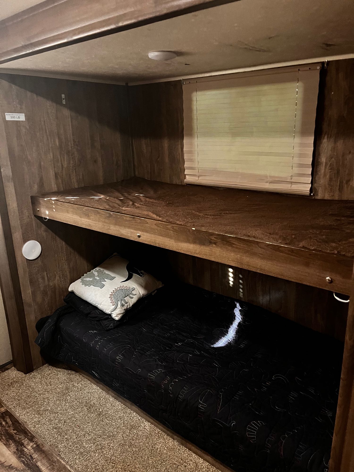 Cozy bunk beds in an RV rental, featuring wood paneling, a window with blinds, and a neat sleeping area.. Forest River Palomino Puma XLE 2017