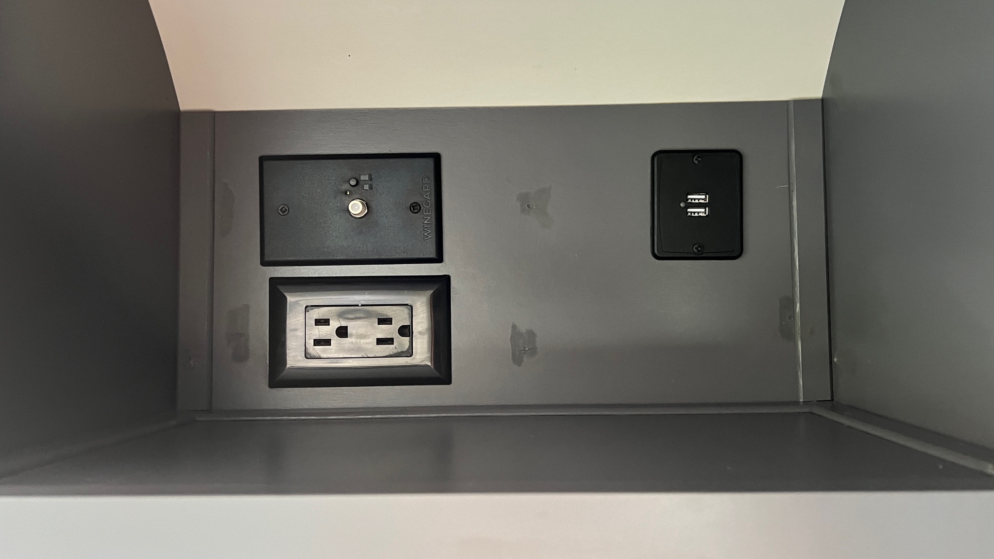 Inside an RV rental: a power panel with a coaxial hookup, standard AC outlet, and dual USB charging ports.. Thor Dazzle 2024