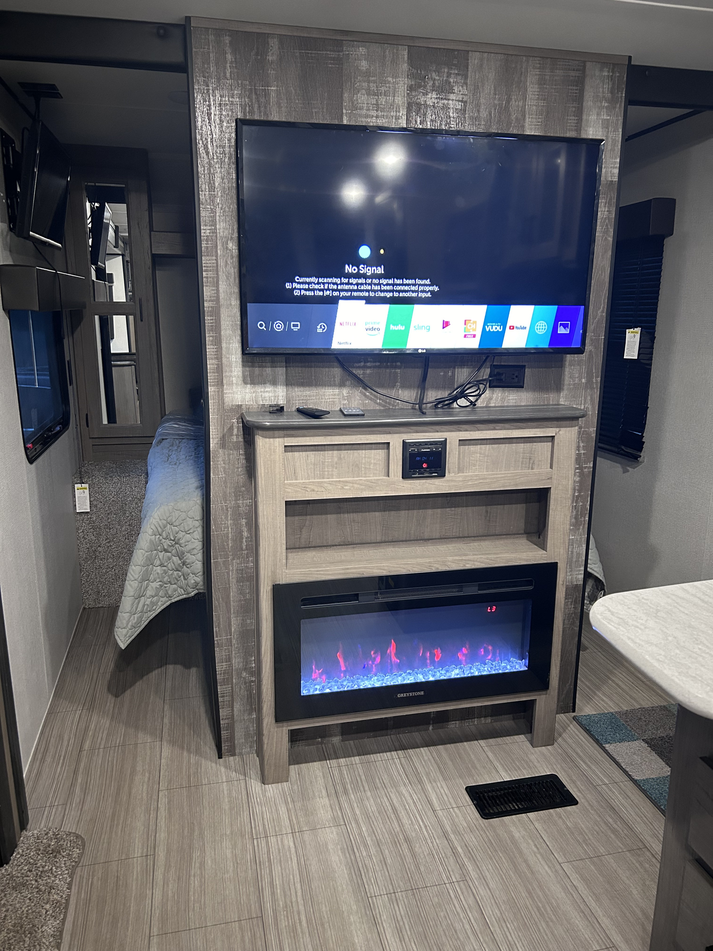 This modern RV rental's living space features a large TV with streaming apps, an electric fireplace, and a cozy bedroom beyond.. Keystone RV Hideout 2021