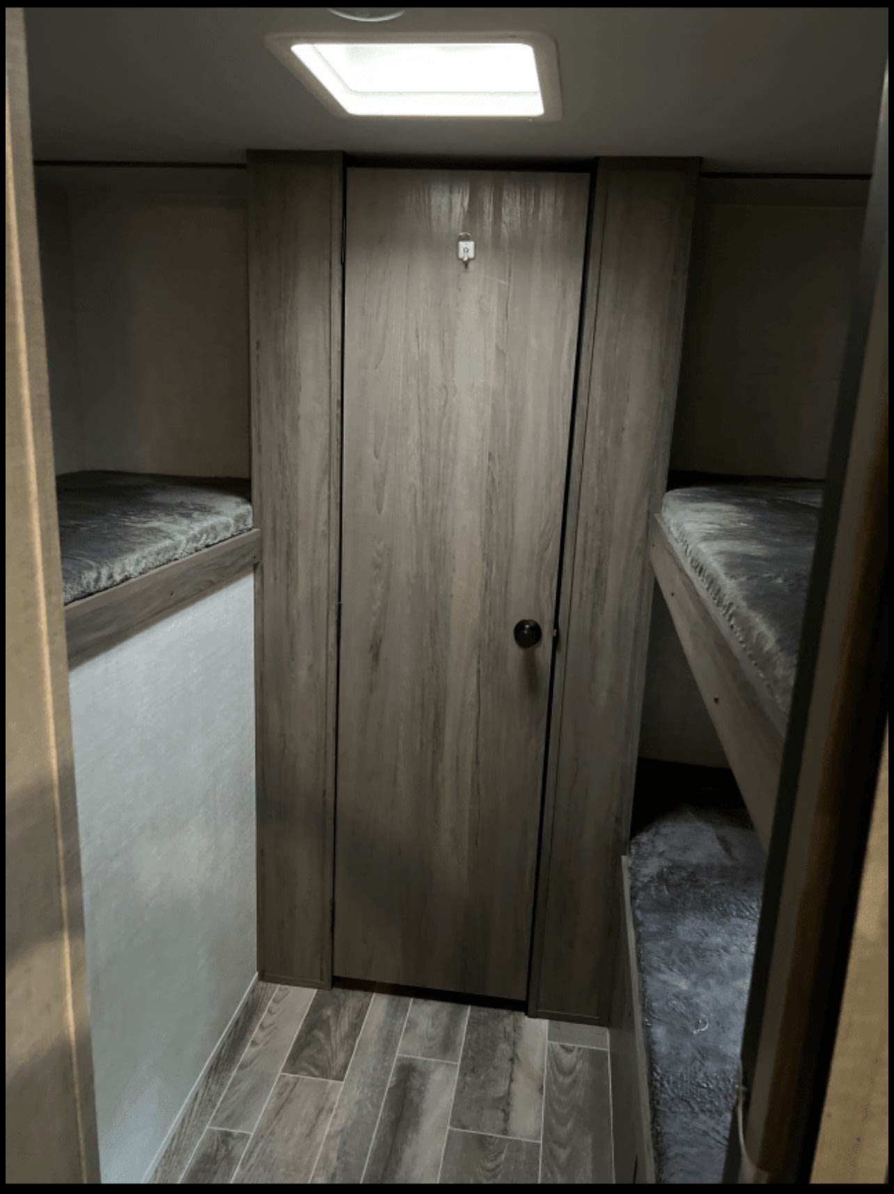 Explore this RV rental's compact interior with bunk beds, wood-look flooring, and a central door, perfect for adventure travel.. Gulf Stream Ameri-Lite 2022