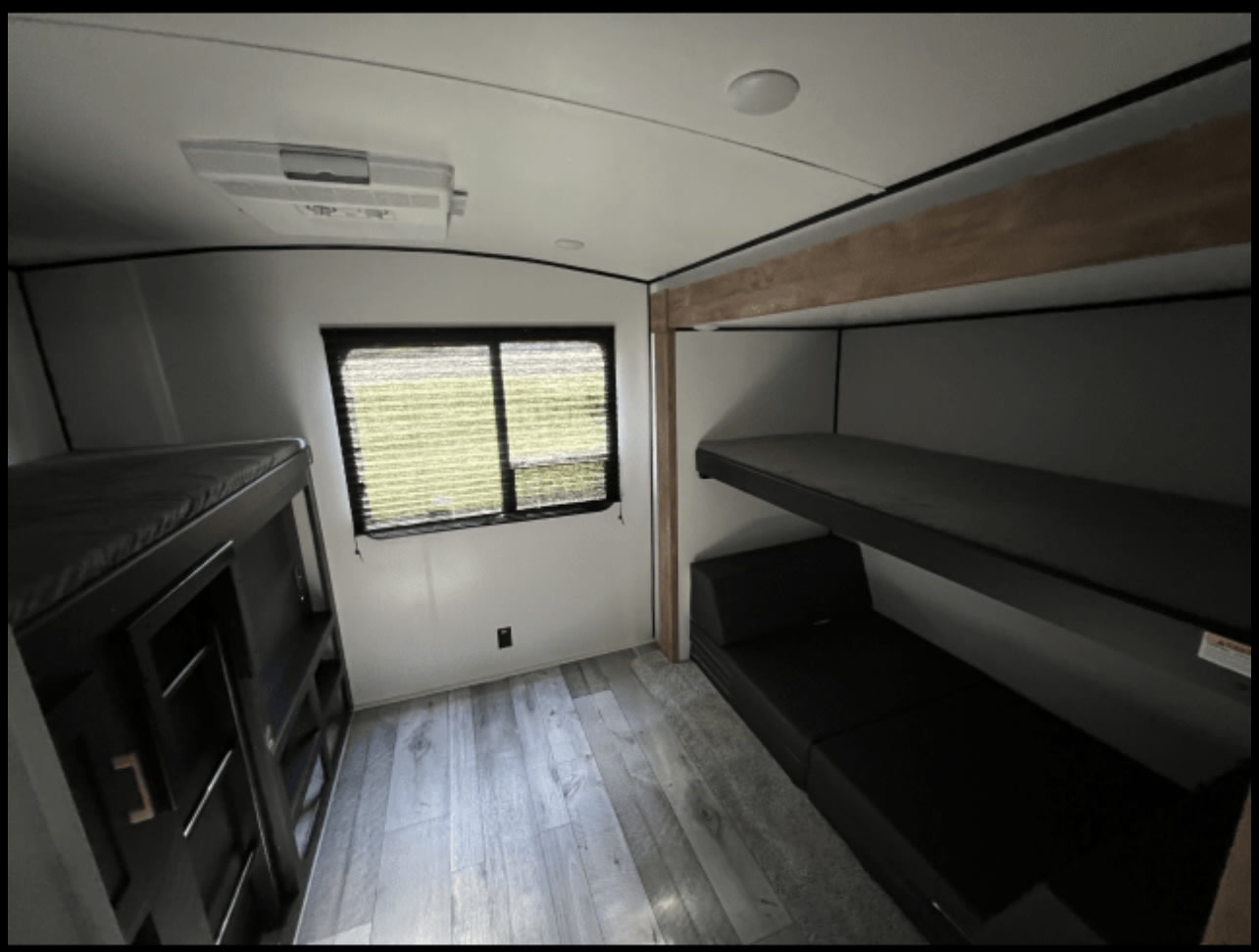 Bright RV rental interior with bunk beds, a convertible sofa, and window, ideal for family trips.. Keystone RV Springdale 2022