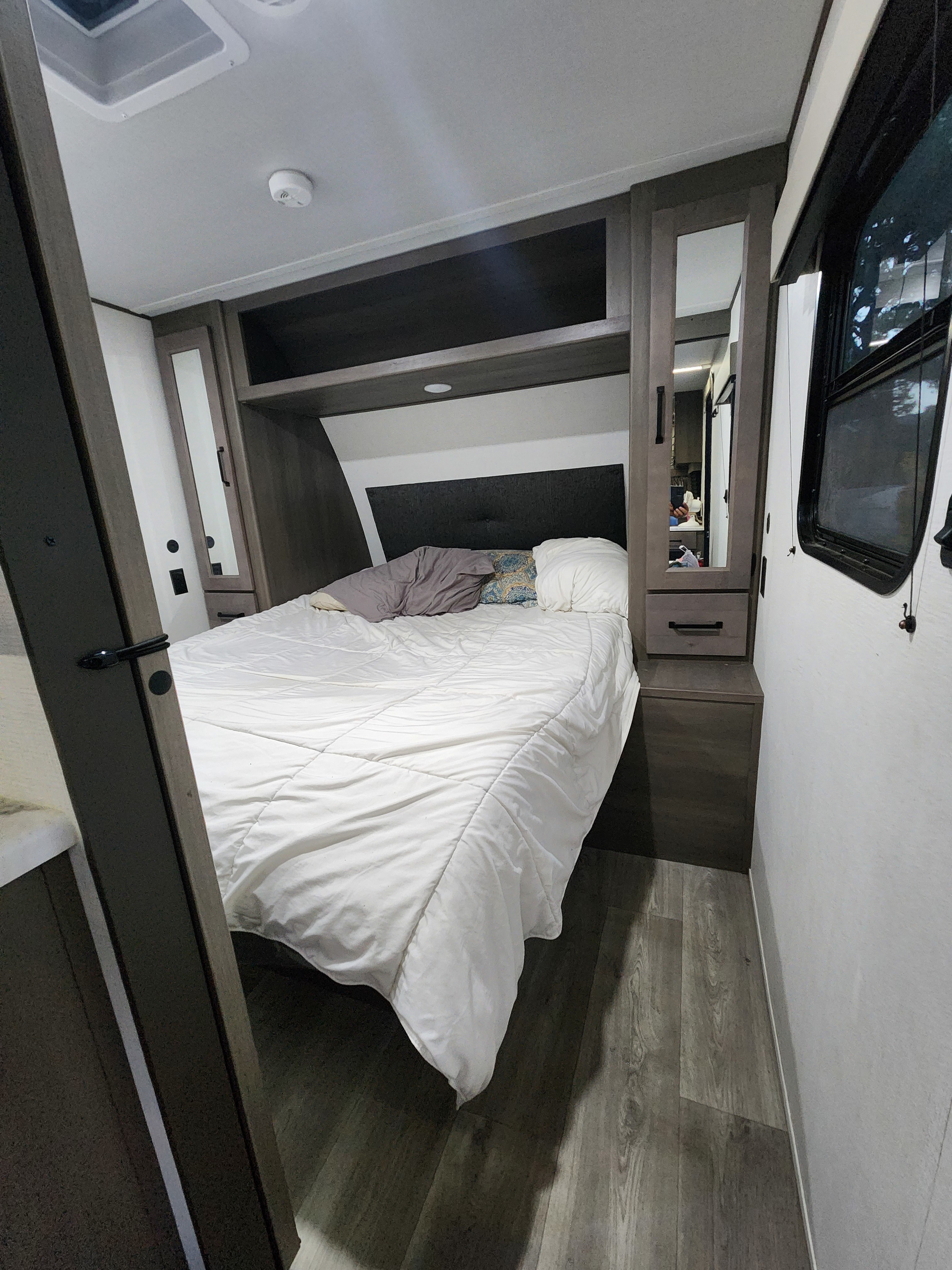 Cozy RV rental bedroom with comfortable bed, built-in storage, and wood-look floor. Ideal for your mobile adventures.. Grand Design Transcend Xplor 2024