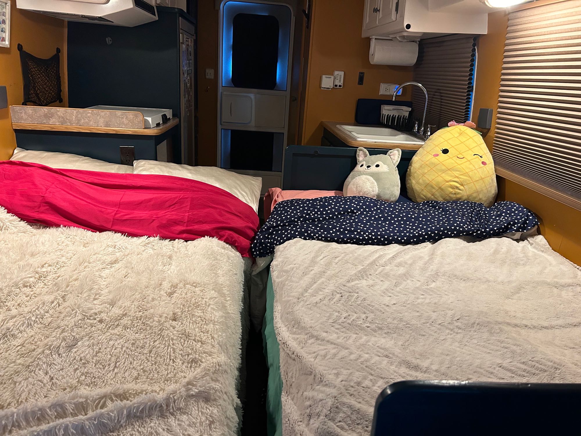 Inside a vibrant RV rental: two beds with soft blankets & stuffed animals, plus a functional compact kitchen.. R-Vision Trail-Lite B+ 2003