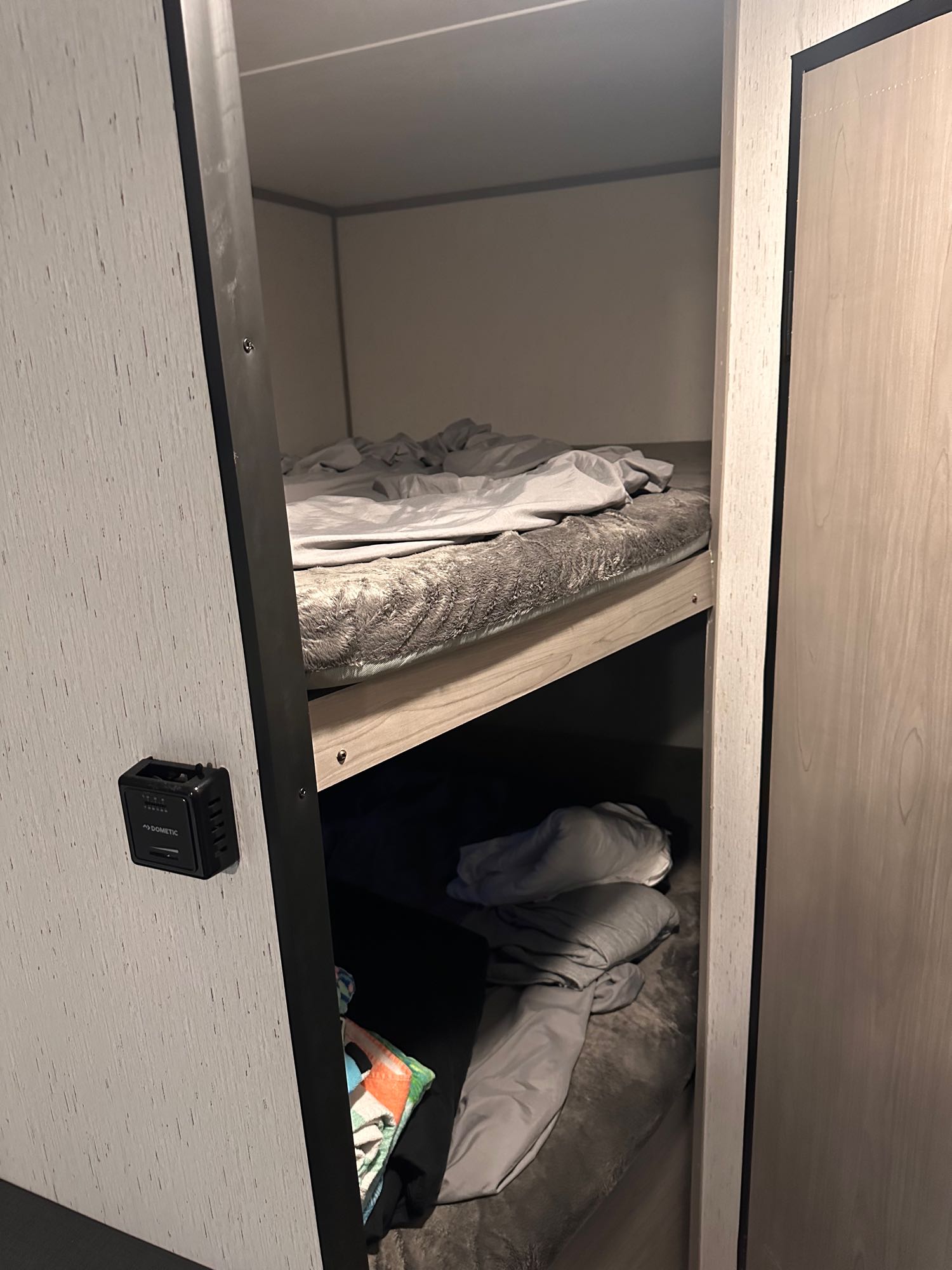 Inside an RV rental, two bunk beds with soft grey bedding provide cozy sleeping. A Dometic control is on the wall.. Dutchmen Coleman Lantern LT 2023