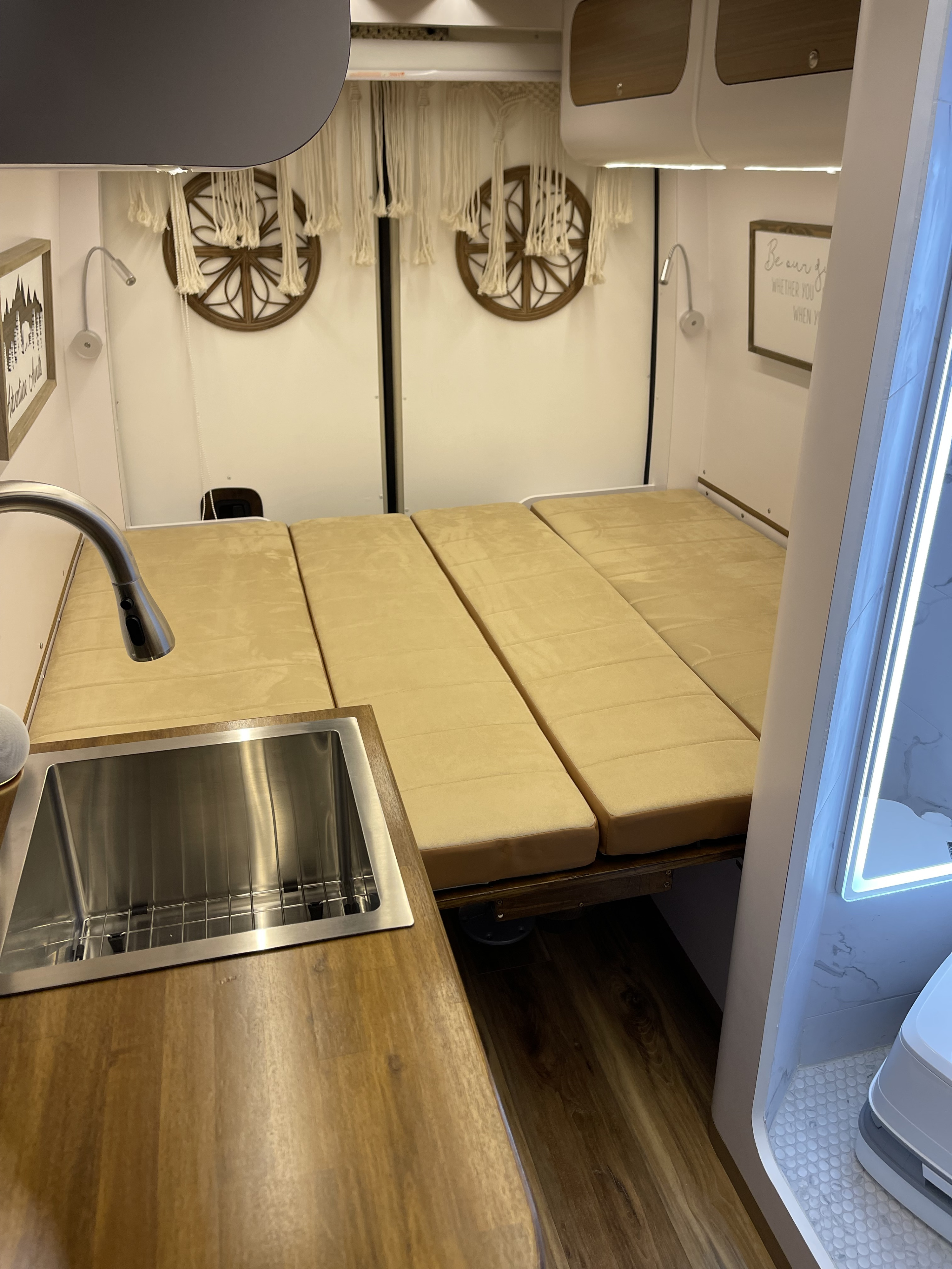 This RV rental offers a compact kitchen with a stainless steel sink, a cozy bed, and overhead storage, ideal for travel.. Mercedes-Benz sprinter 2022