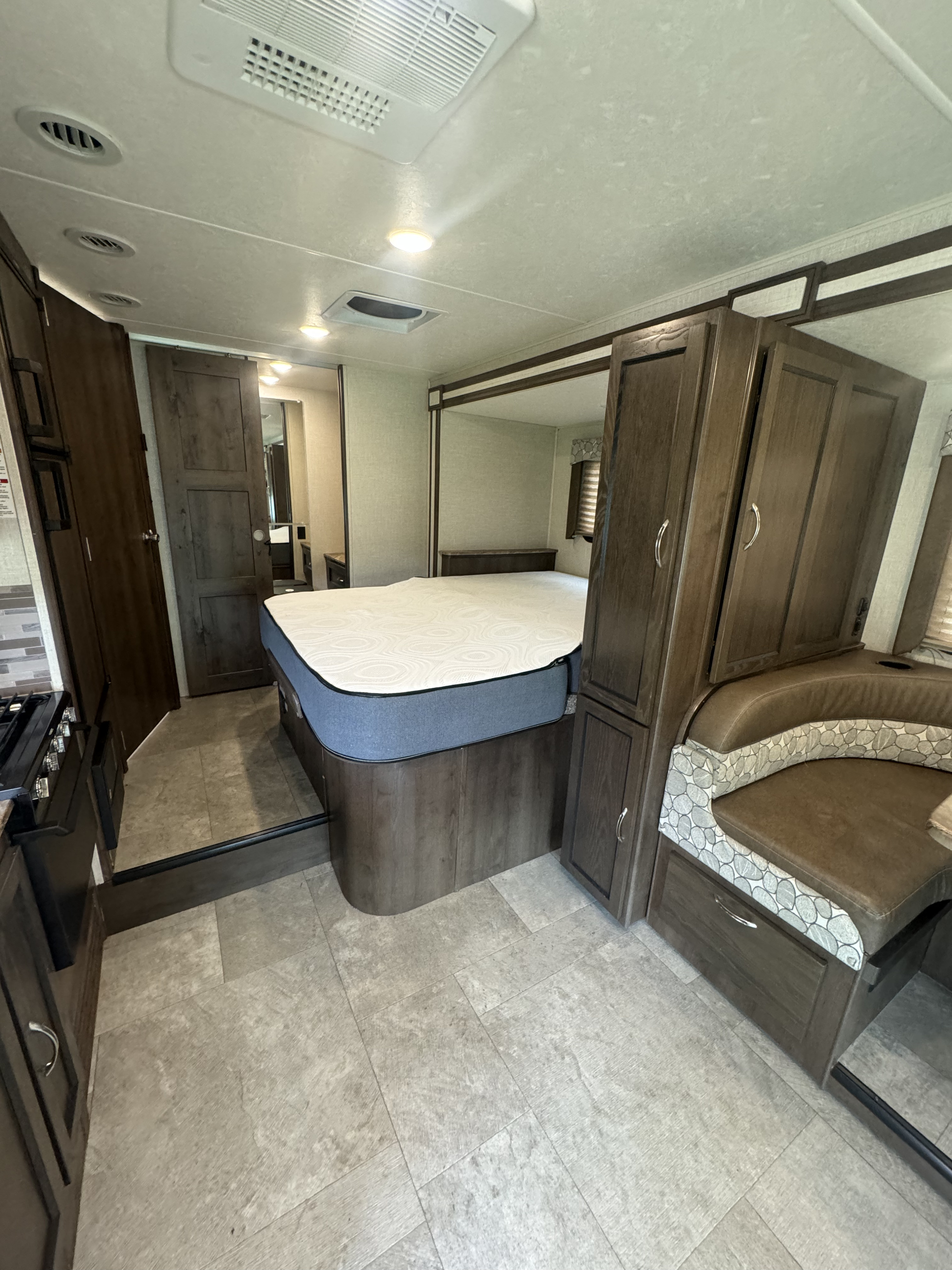 RV rental interior showcasing a cozy bedroom area, dinette, and sleek kitchen setup with modern cabinetry.. Coachman freelander 2020