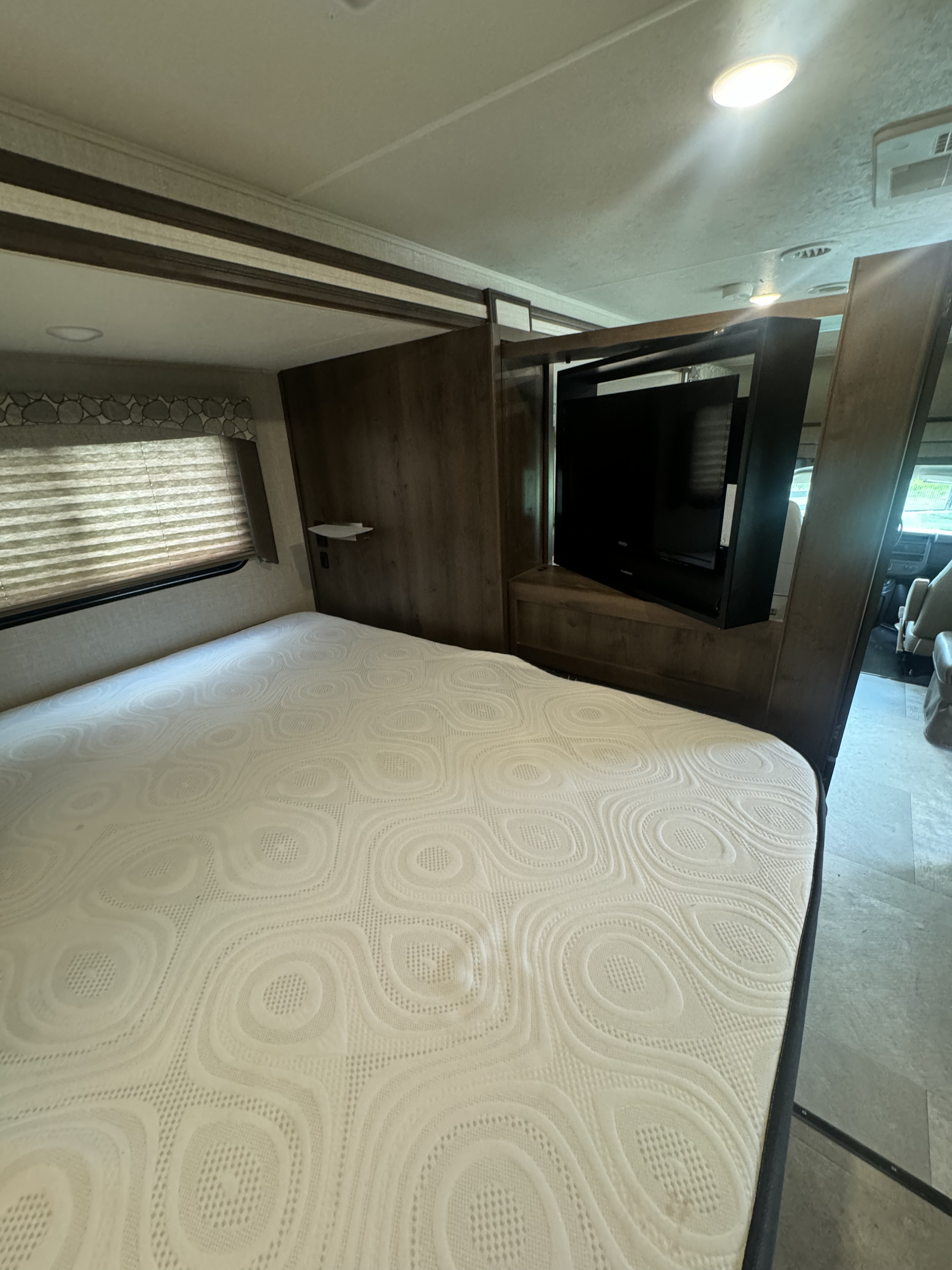 RV rental bedroom: a cozy interior with a patterned mattress, window with blinds, and a mounted TV. Ideal for travel.. Coachman freelander 2020