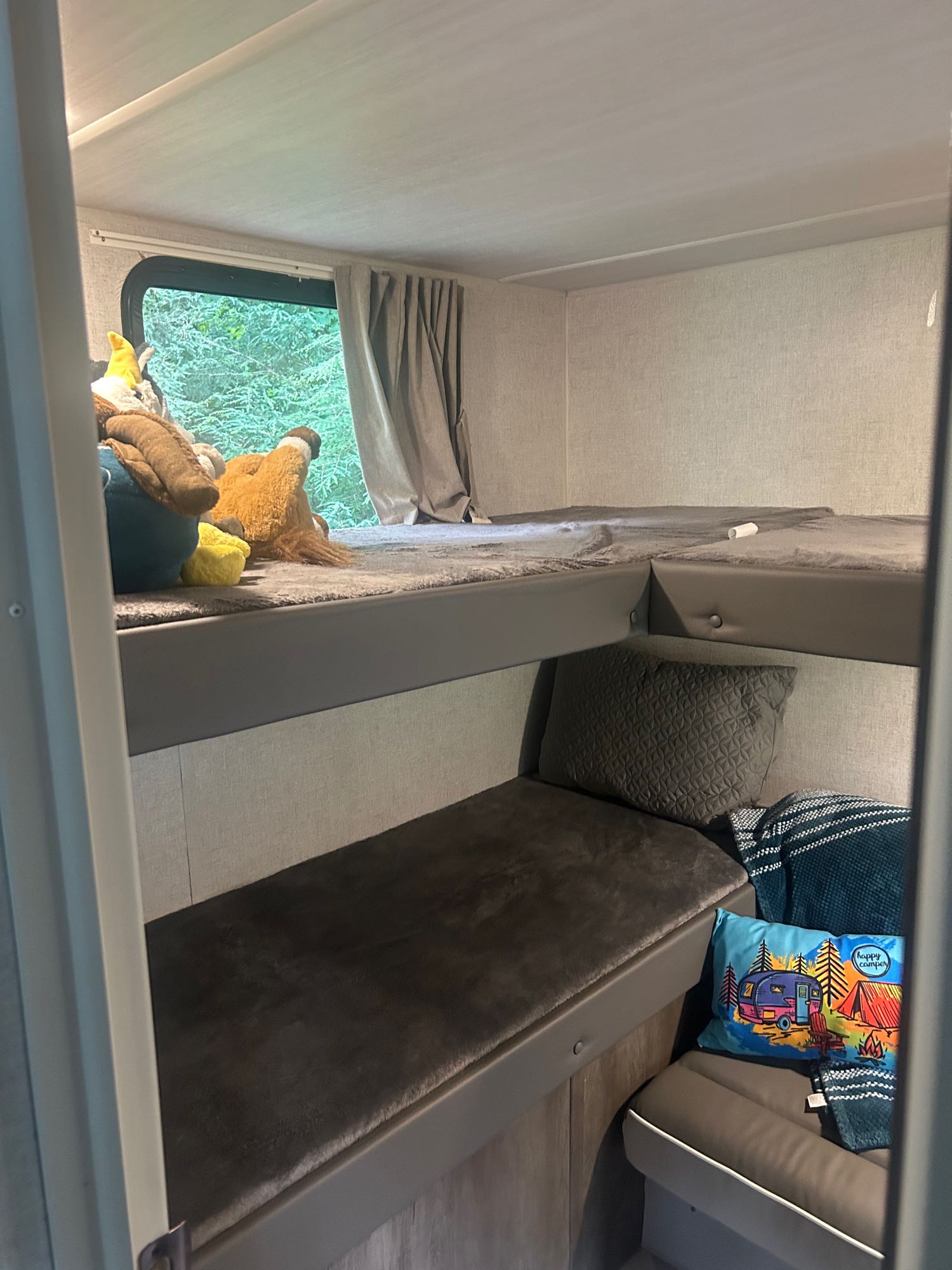 Cozy RV rental bunk beds, perfect for families. Features stuffed animals & a 'Happy Camper' pillow. Ideal for travel adventures.. Forest River Salem Cruise Lite 2021