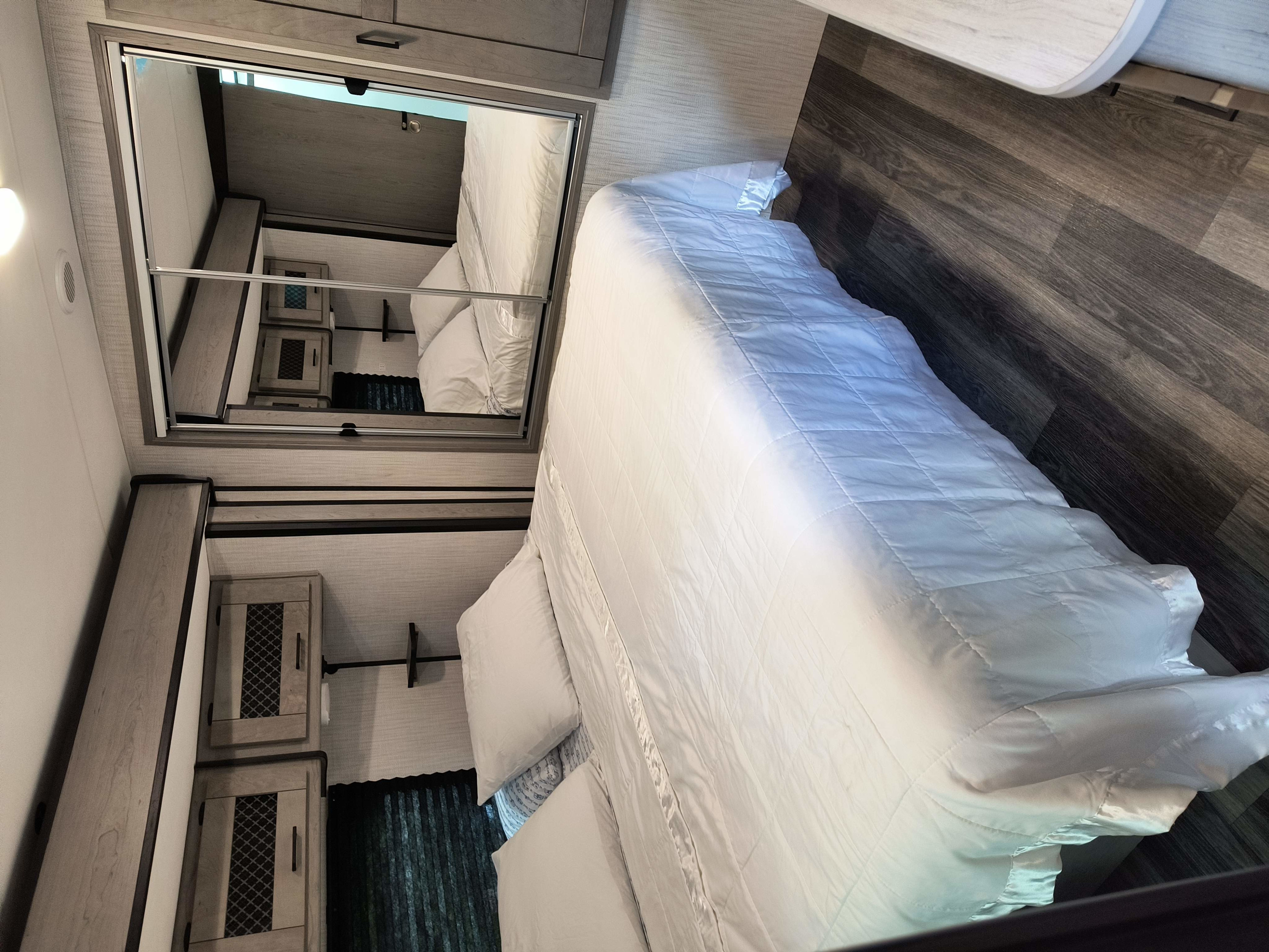 Experience comfort in this RV rental bedroom with a cozy bed, mirrored closet, and convenient overhead storage.. Heartland RVs Mallard 2021