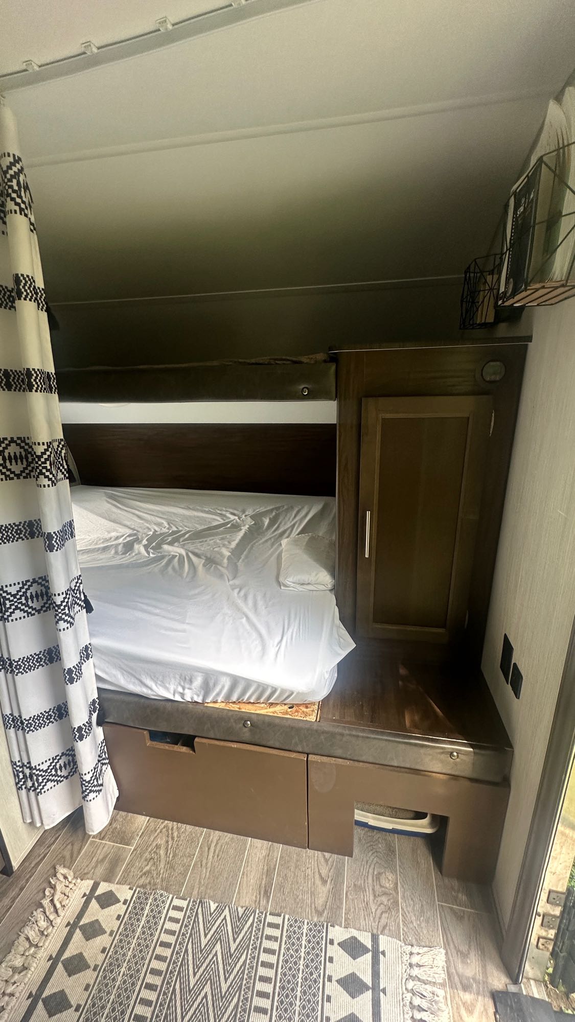 Cozy RV rental bunk bed area: White sheets, under-bed storage drawers, and a discreet cat litter box. Black/white patterned curtain.. Forest River Other 2019