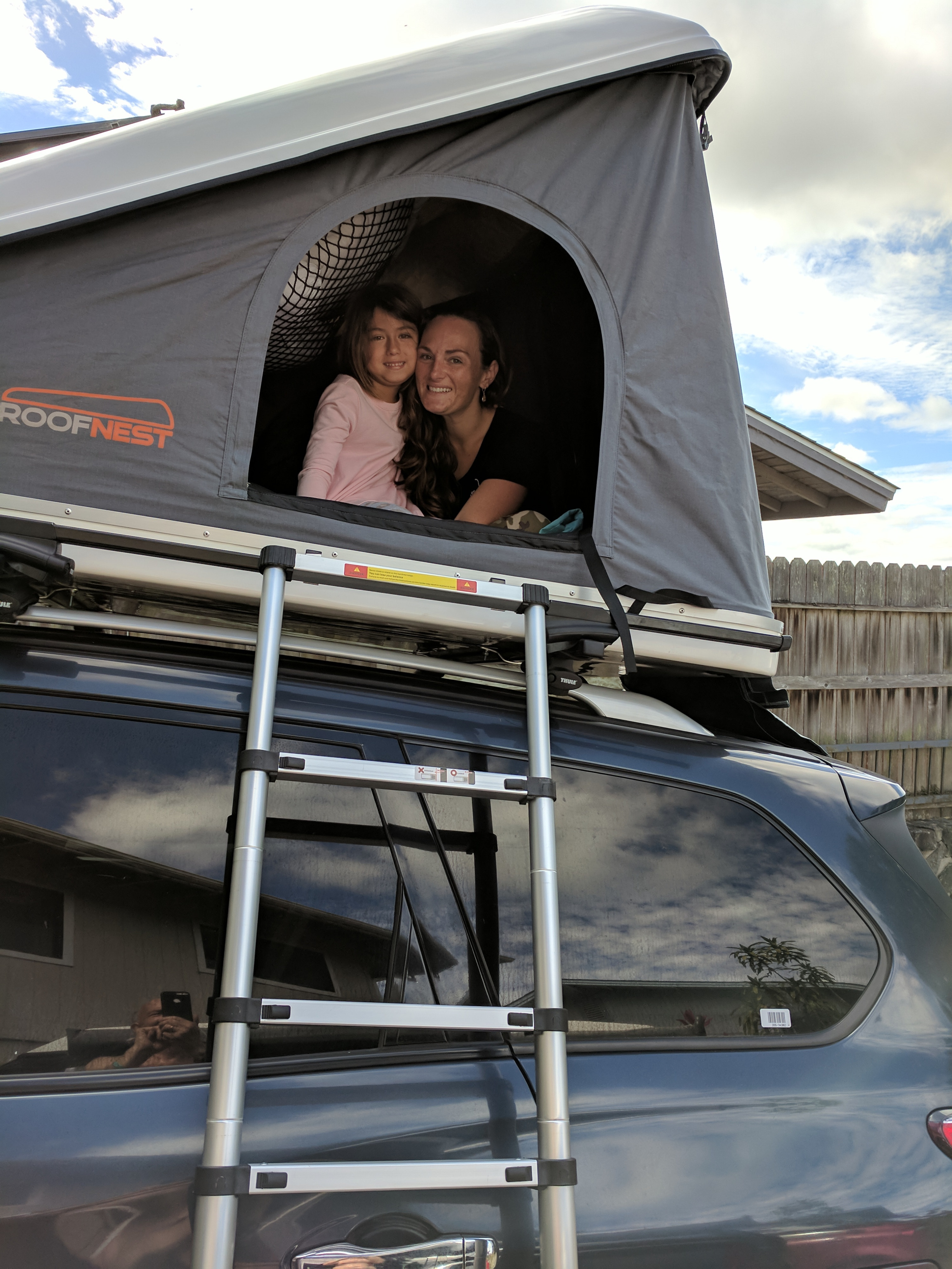 Smiling mom & daughter enjoy a gray Roofnest rooftop tent on a vehicle. Perfect for your next rv rental camping adventure!. Nissan Pathfinder 2016