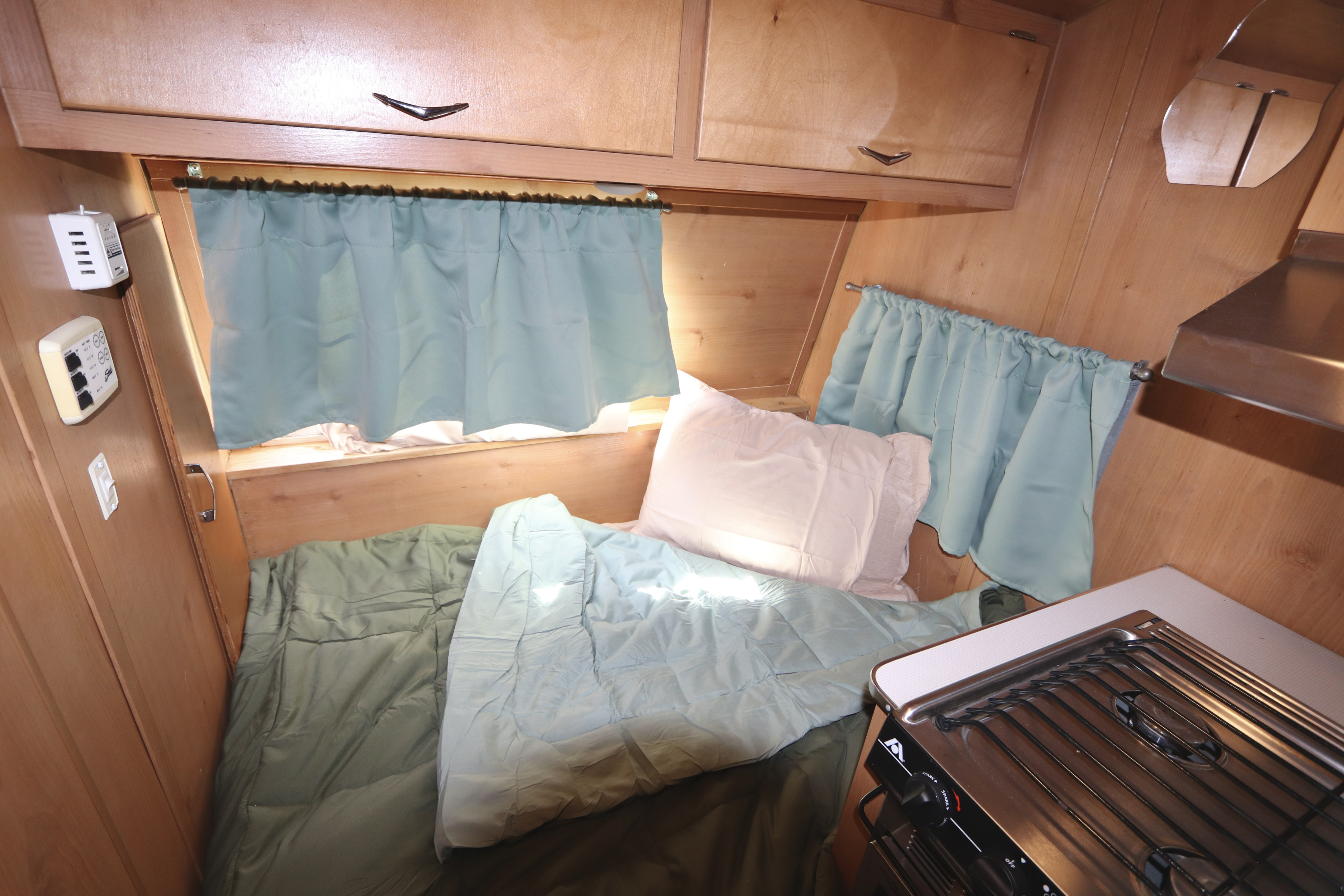 Experience this cozy RV rental's bedroom and kitchen. Features wooden interior, soft bedding, and natural light.. Shasta Airflyte 2016