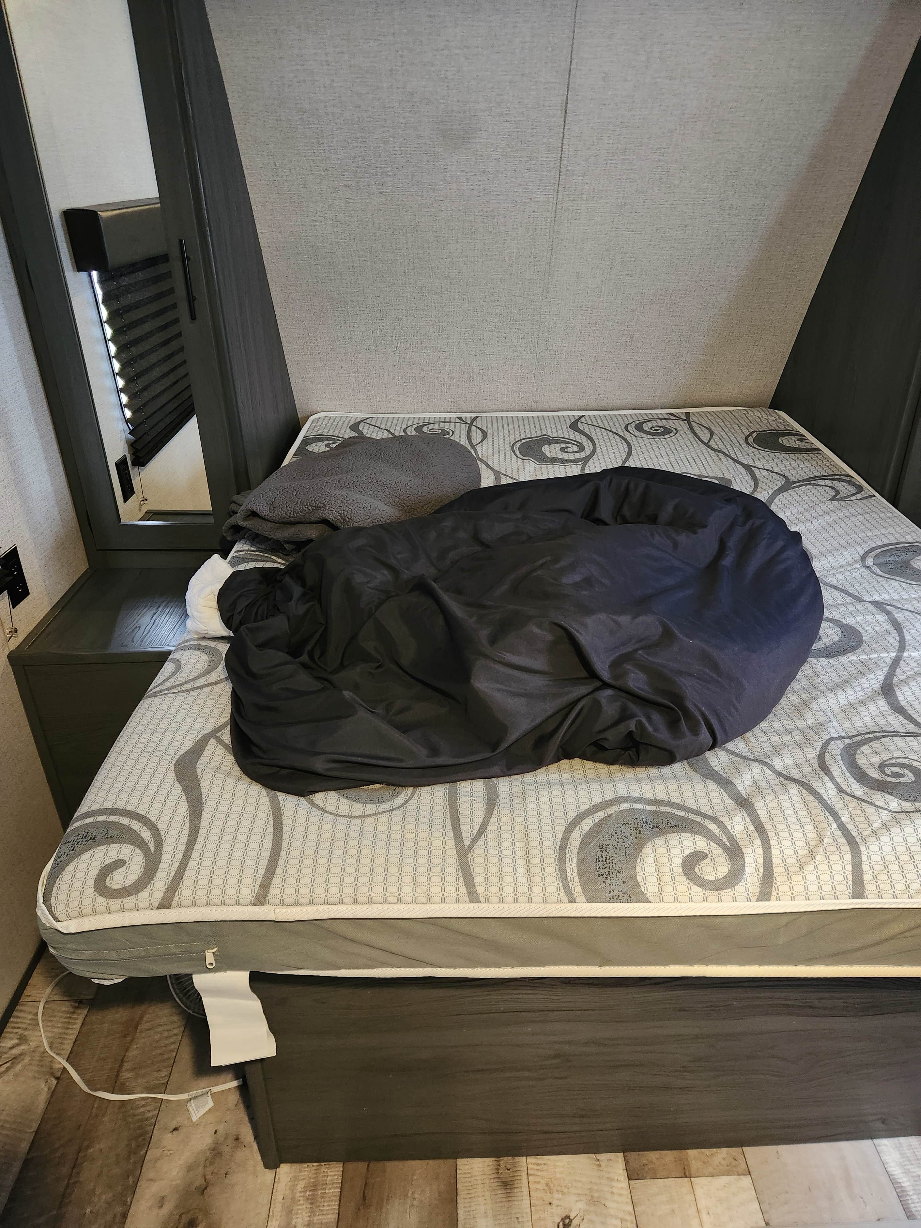 RV rental bedroom featuring a patterned mattress, black comforter, and compact design.. Dutchmen Aspen trail 29bb 2021