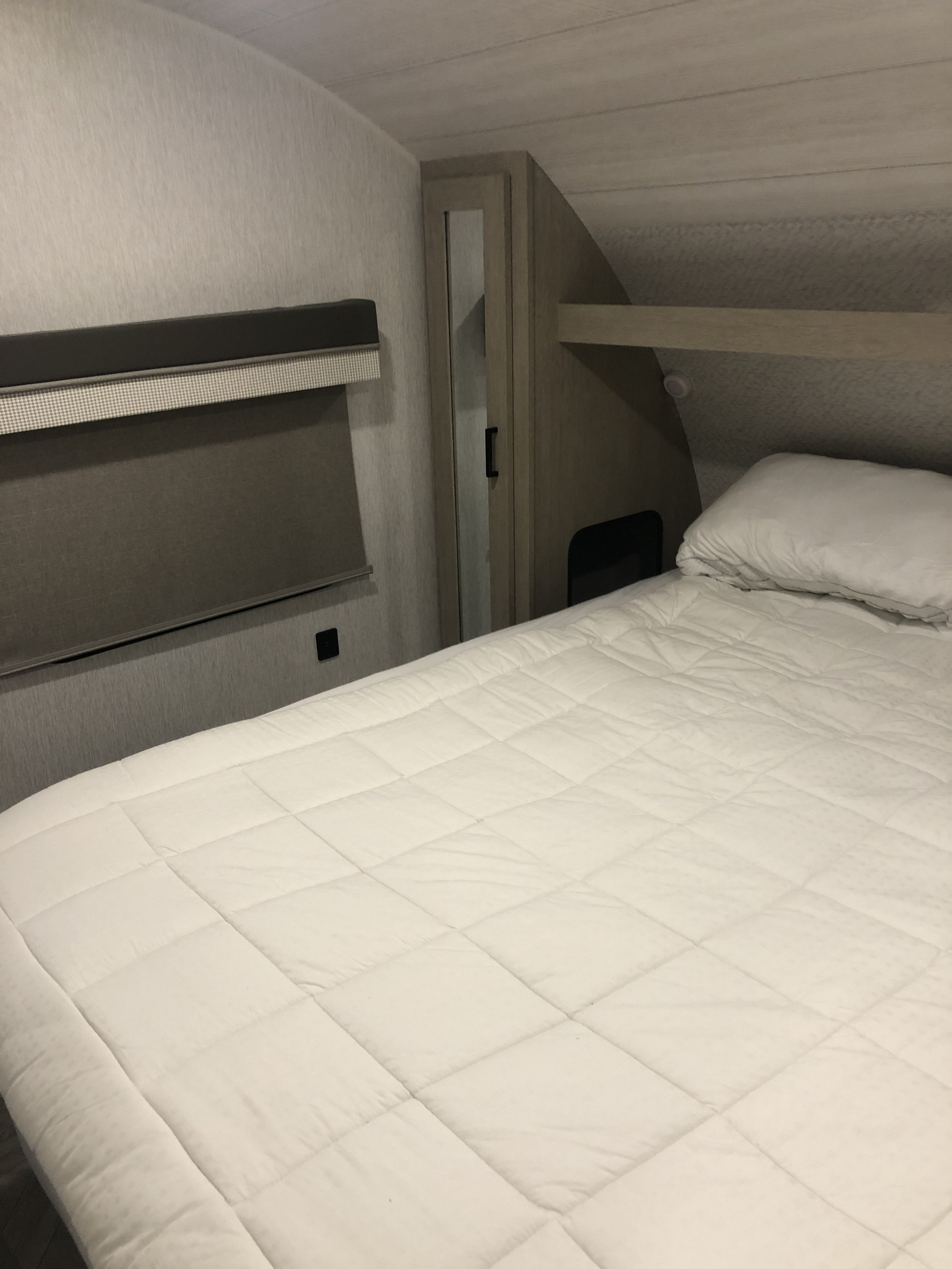 Cozy RV rental bedroom featuring a comfortable bed, window with shades, overhead storage, and compact design.. Forest River Salem Cruise Lite Platinum 2023