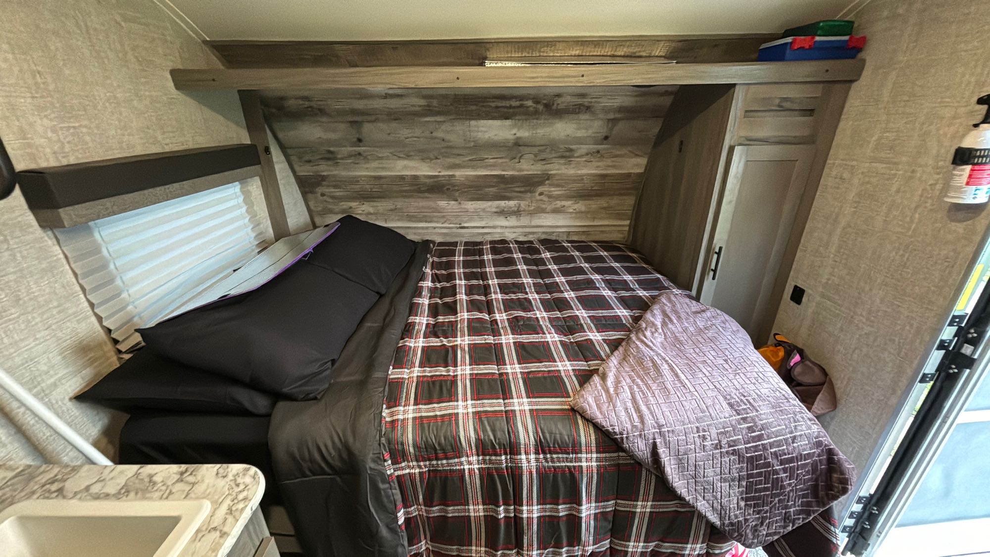 Inside an RV rental: a cozy bedroom with plaid bedding, a window, and wood-paneled walls.. Gulf Stream Ameri-Lite Super Lite 2021