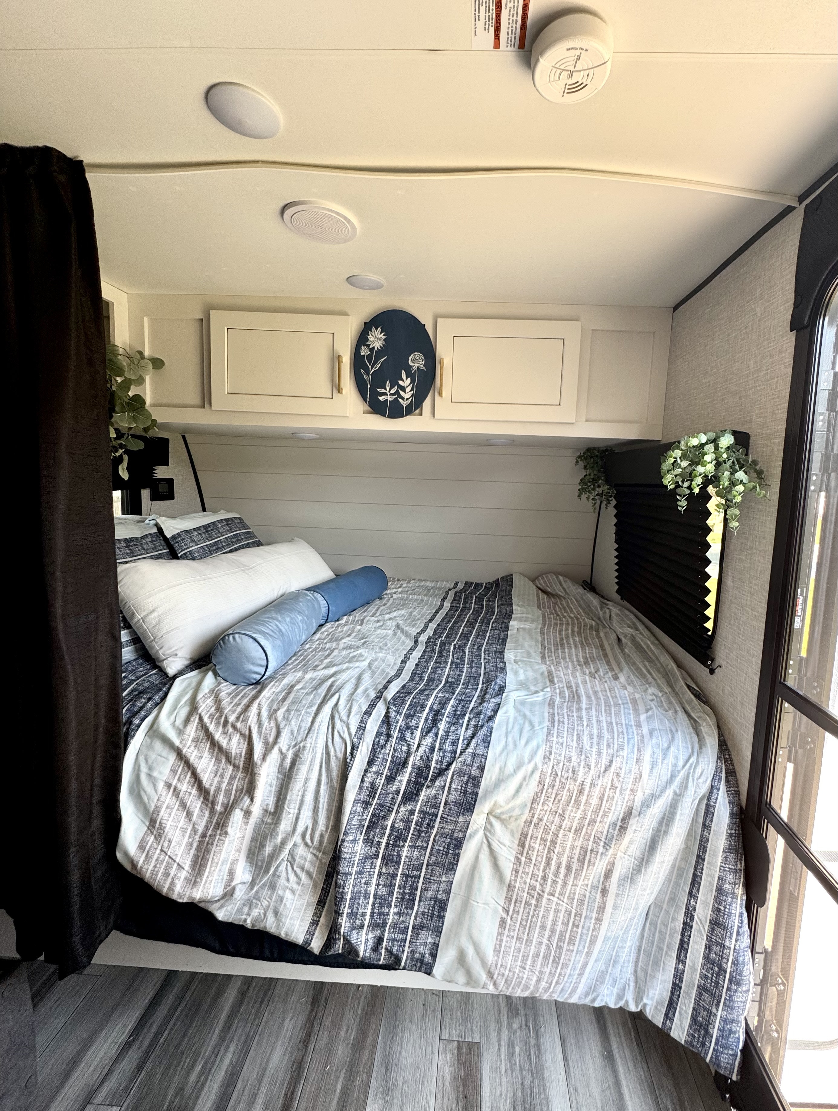 Cozy RV rental bedroom with striped bedding, overhead cabinets, and shiplap wall decor, offering a comfortable stay.. Jayco Jay Flight SLX Baja Edition 2024
