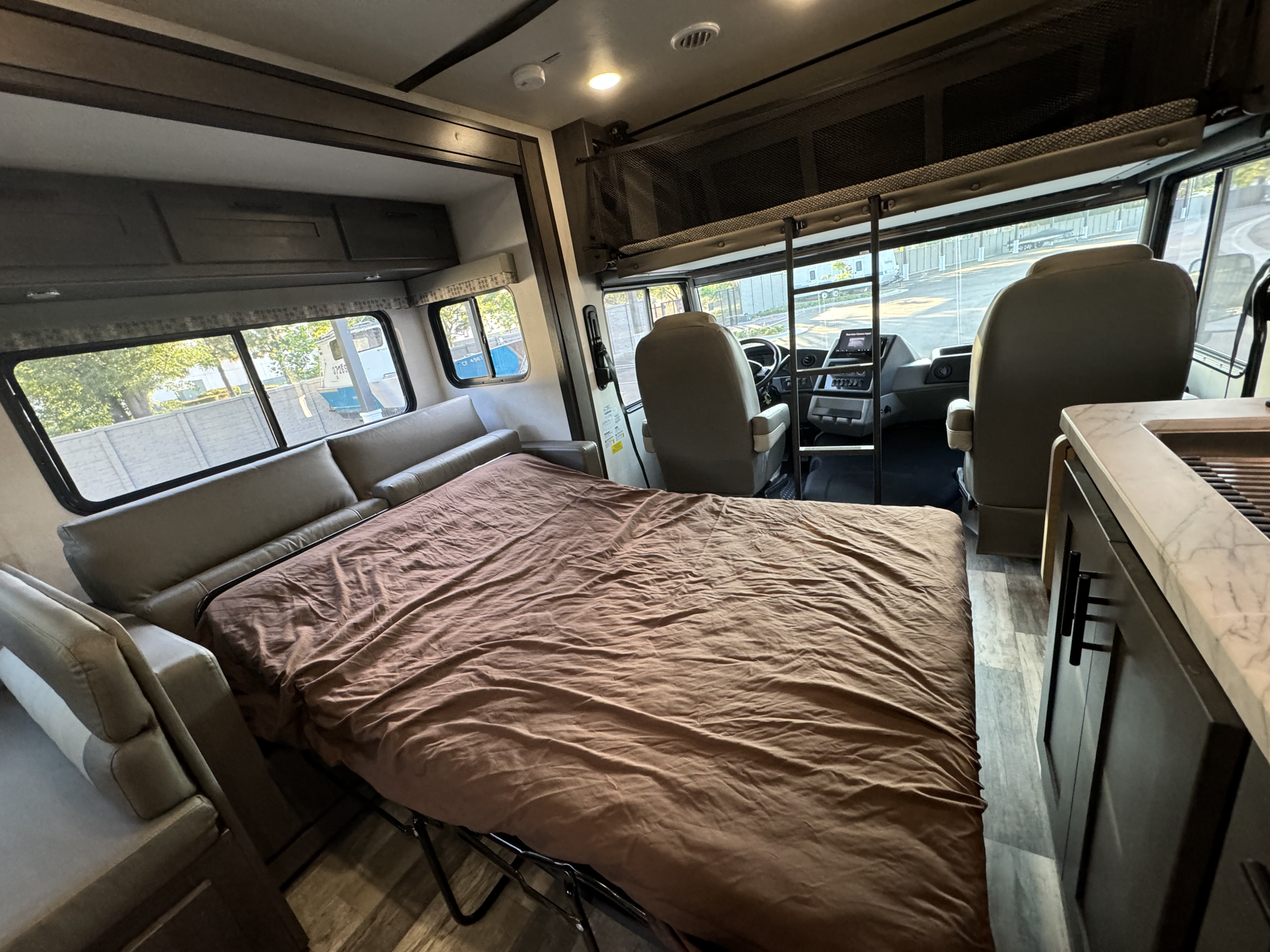 An RV rental's spacious interior with a cozy pull-out bed, driver's area, kitchenette, and overhead bunk.. Forest River Fr3 2021