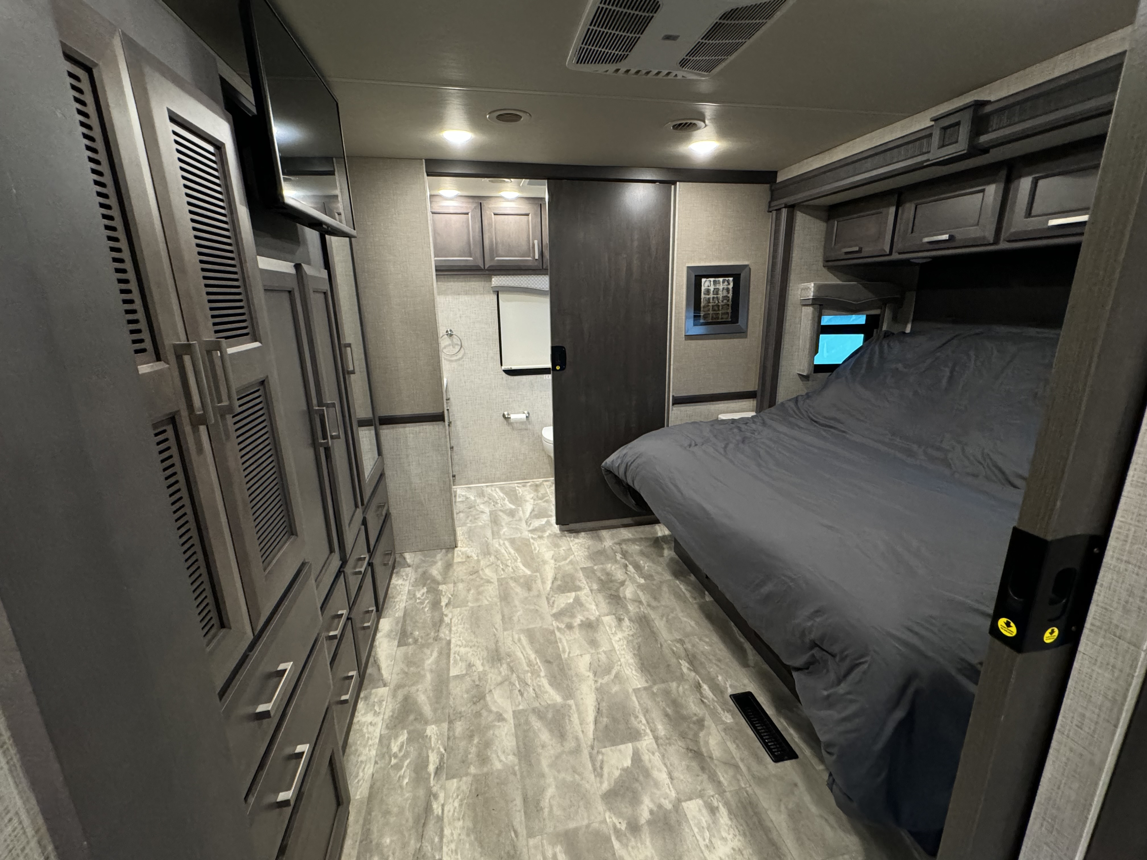 Spacious RV rental bedroom with wardrobe, comfortable bed, and accessible ensuite bathroom. Features modern grey interior.. Thor Motor Coach CHALLENGER 37DS 2023