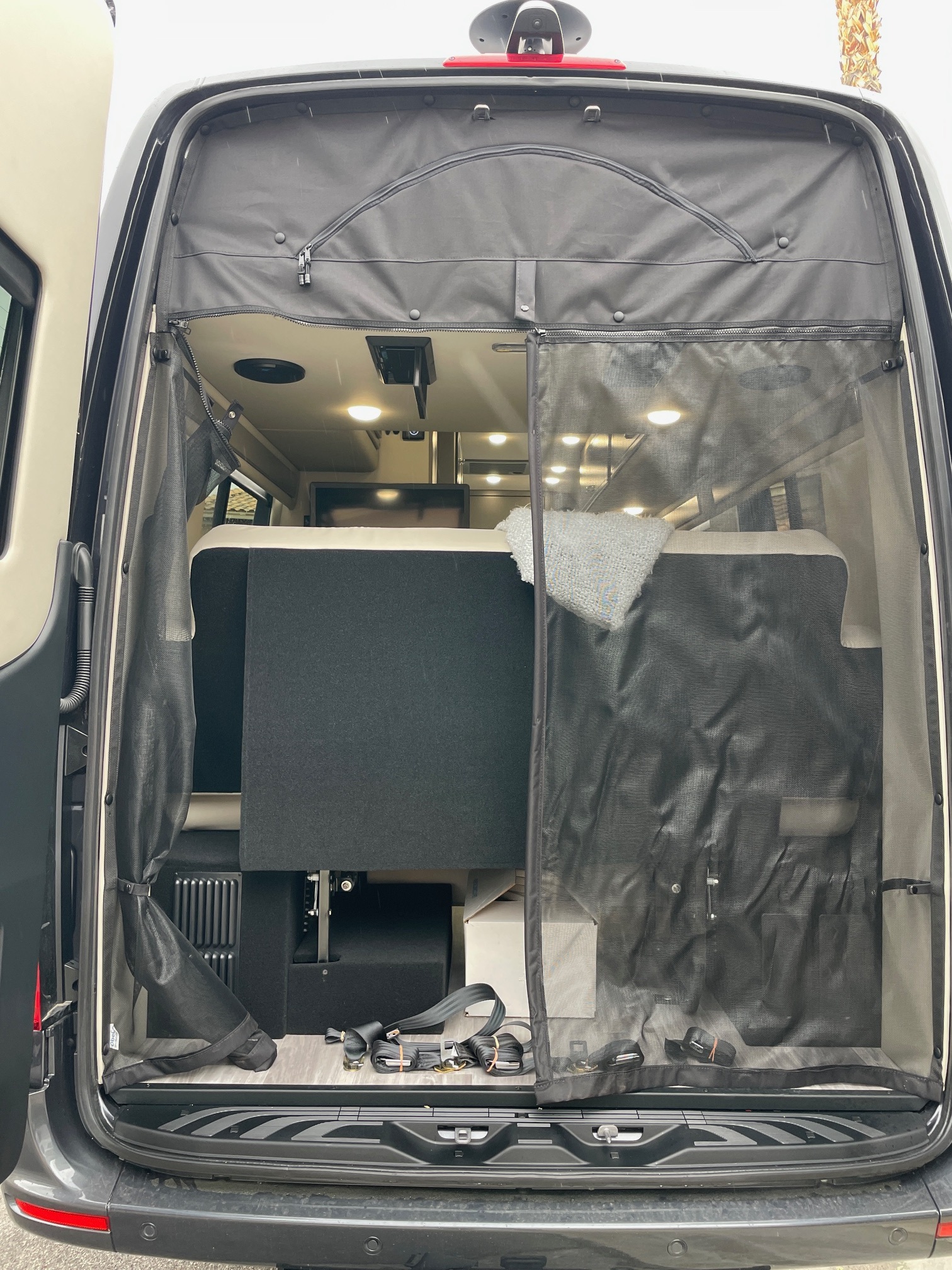 This RV rental's rear doors are open, revealing a versatile camper van interior with a deployed mesh screen.. Holiday Rambler Expedition 2024