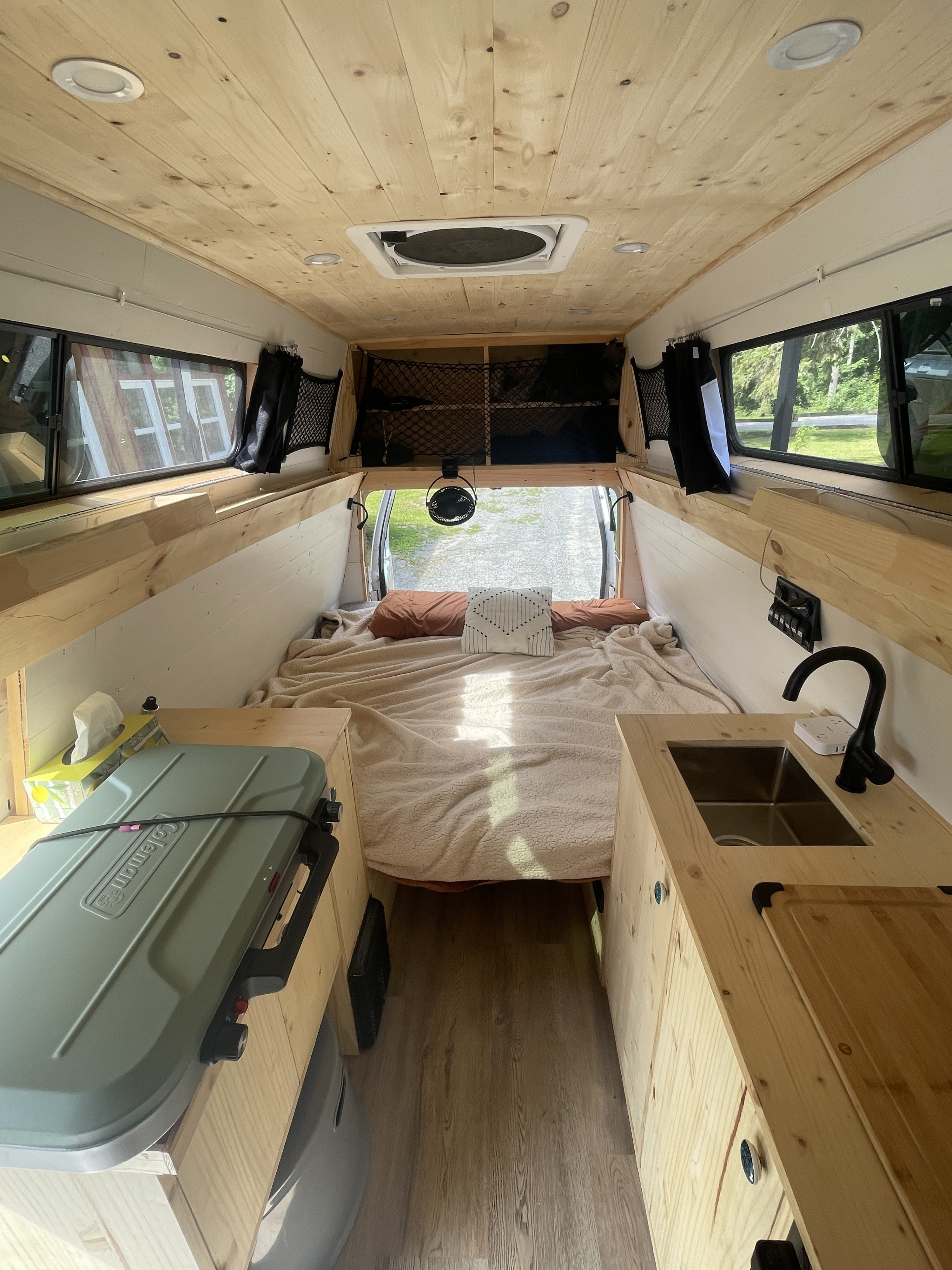 Cozy RV rental interior with a comfy bed, functional kitchen, and bright wood paneling. Your adventure awaits!. Ford Econolline 250s 2011