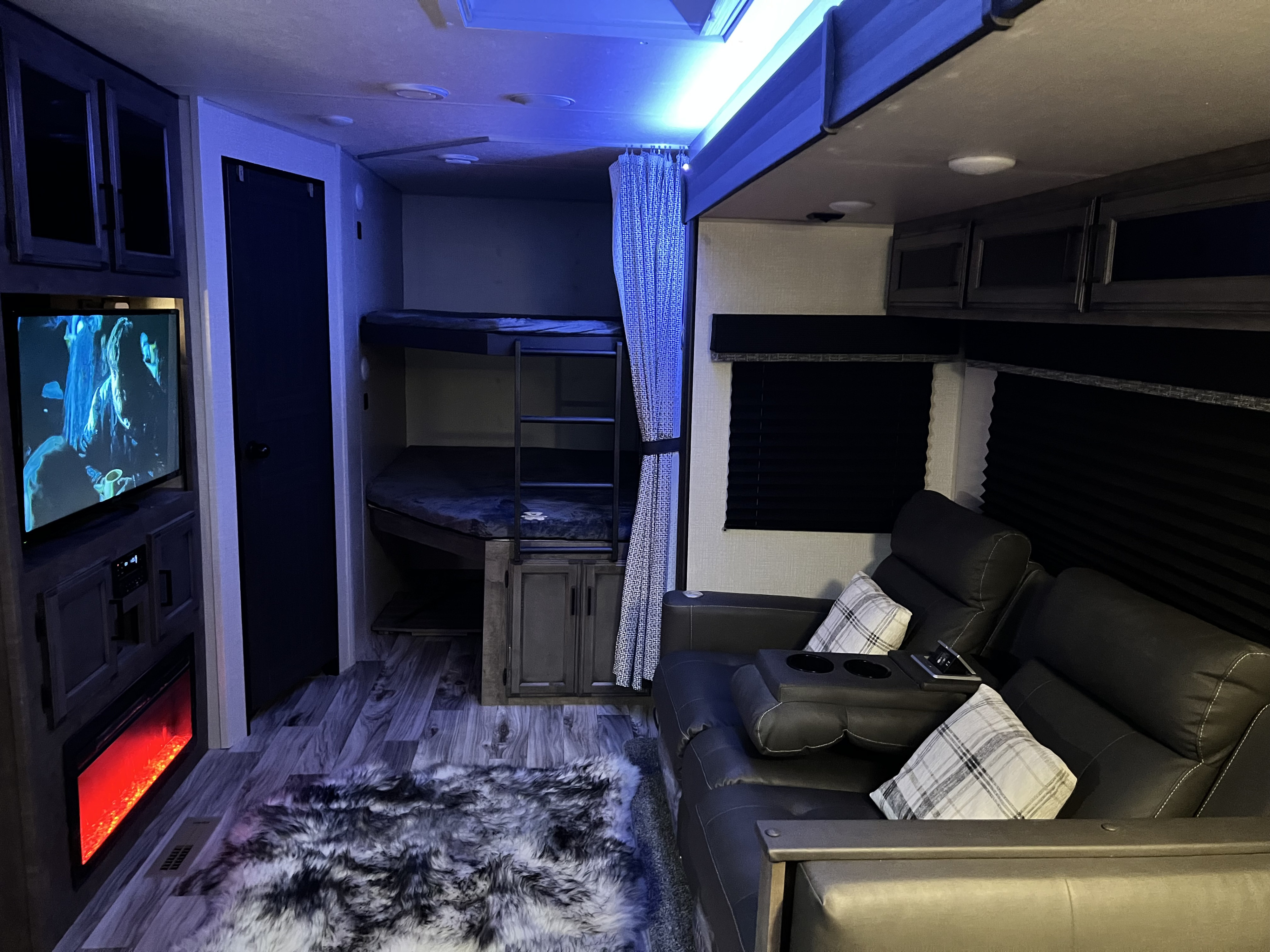 Modern RV rental with comfy recliners, TV, electric fireplace, and bunk beds. Blue LED lighting creates a cozy ambiance.. Venture SportTrek Touring Edition STT312VBH 2021